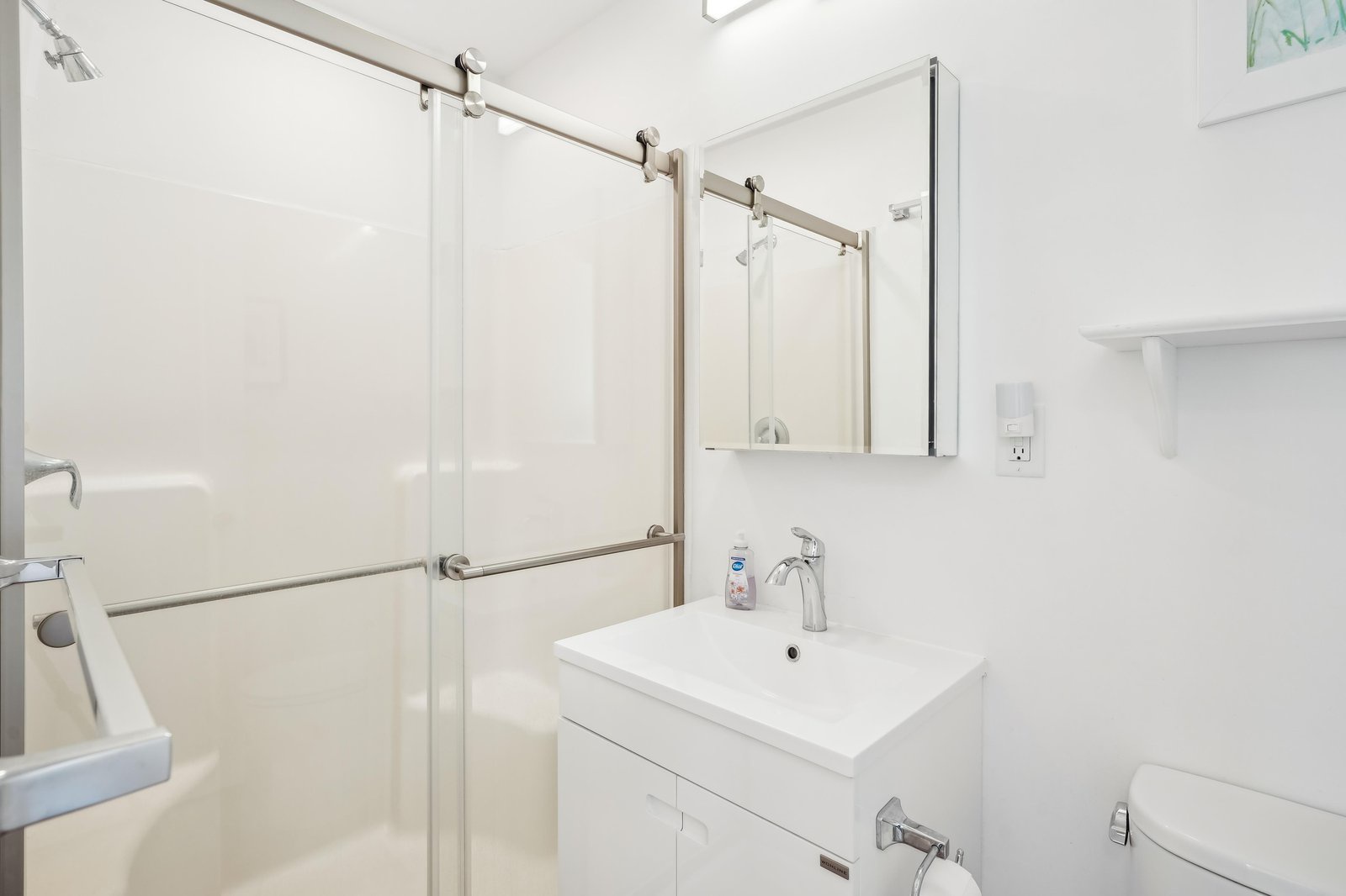 Your bathroom offers a sleek, modern design with a spacious glass-enclosed shower, crisp white vanity, and spotless finishes—a bright, refreshing space to start your day.