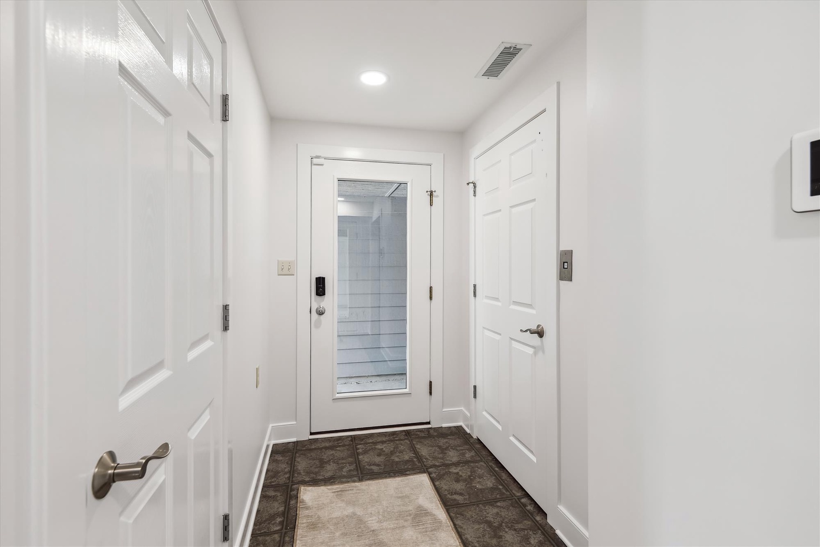 Clean, modern entryway with privacy and secure access. Multiple rooms branch off from this bright, tiled foyer—your private retreat awaits just beyond these doors.
