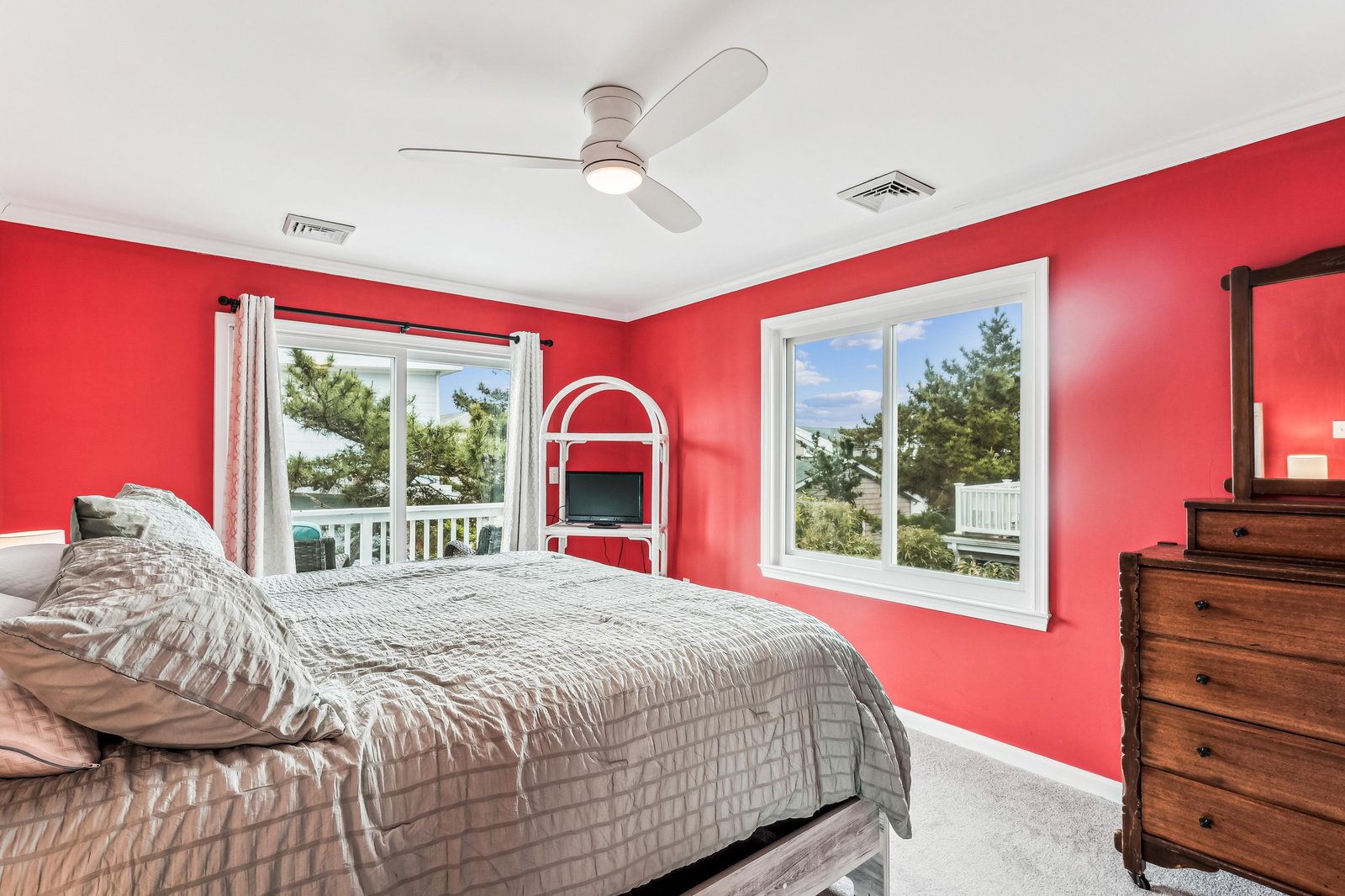 Wake up to natural light and lush tree views framed by large windows. This vibrant bedroom features a cozy fireplace to keep you warm, a ceiling fan for comfort, and plenty of space to unwind.