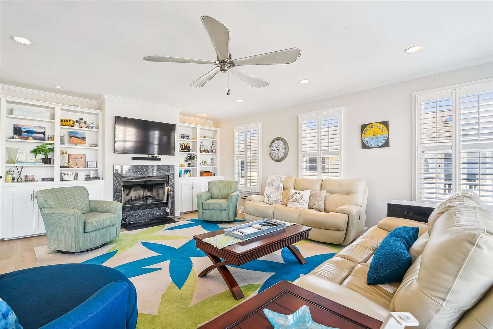 Unwind in your spacious living room with plush seating, a cozy fireplace, and coastal-inspired decor. Natural light fills the space, inviting you to relax and make yourself at home.