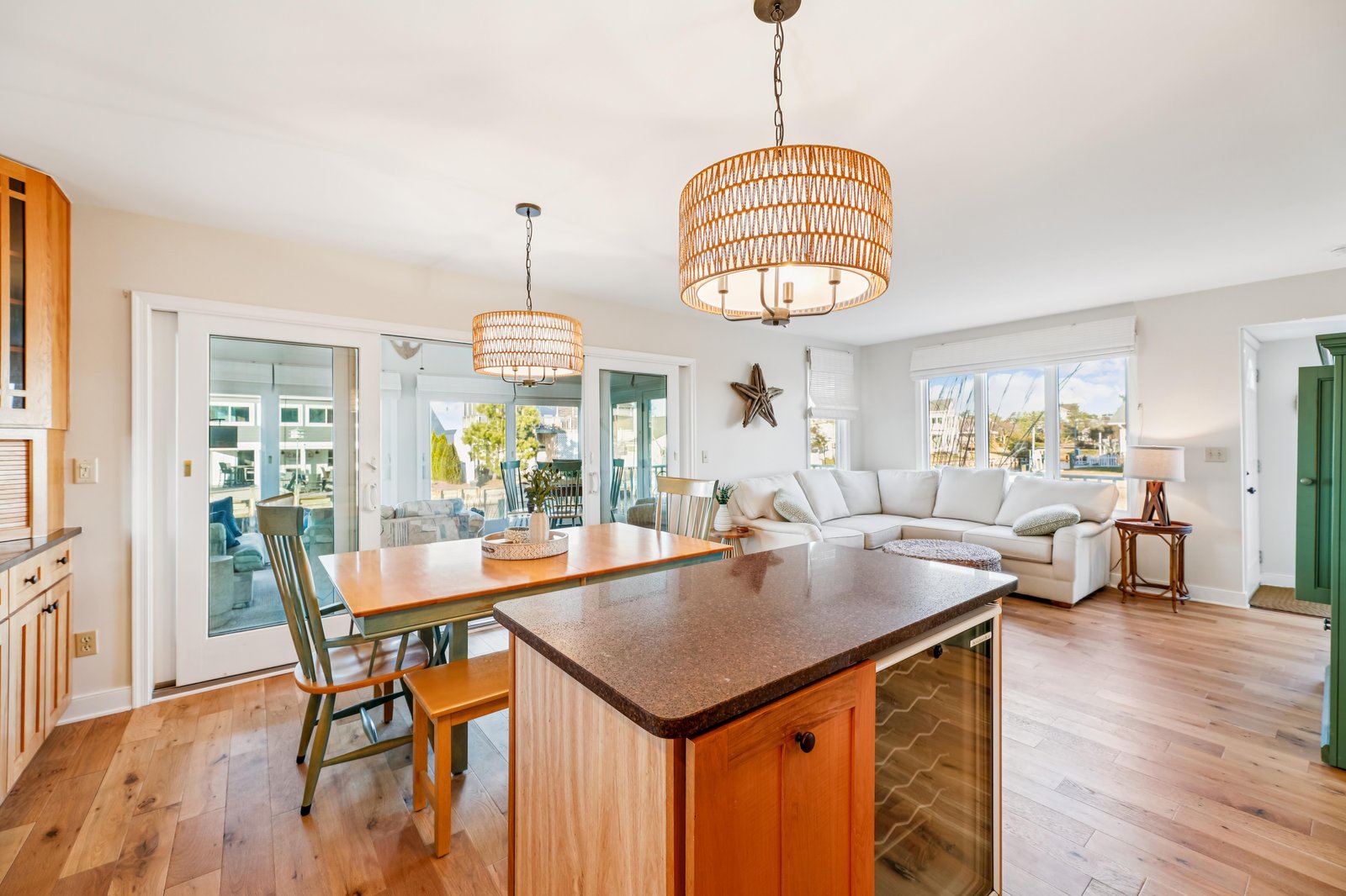 Your bright, open living space invites you to relax with coastal charm, where the dining area flows into cozy seating and water views sparkle beyond glass doors.