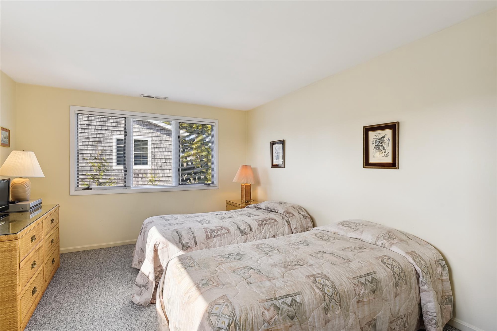 Step into your bright and peaceful guest bedroom, where two twin beds with soft linens promise restful nights and morning light filters through the window to greet your day.