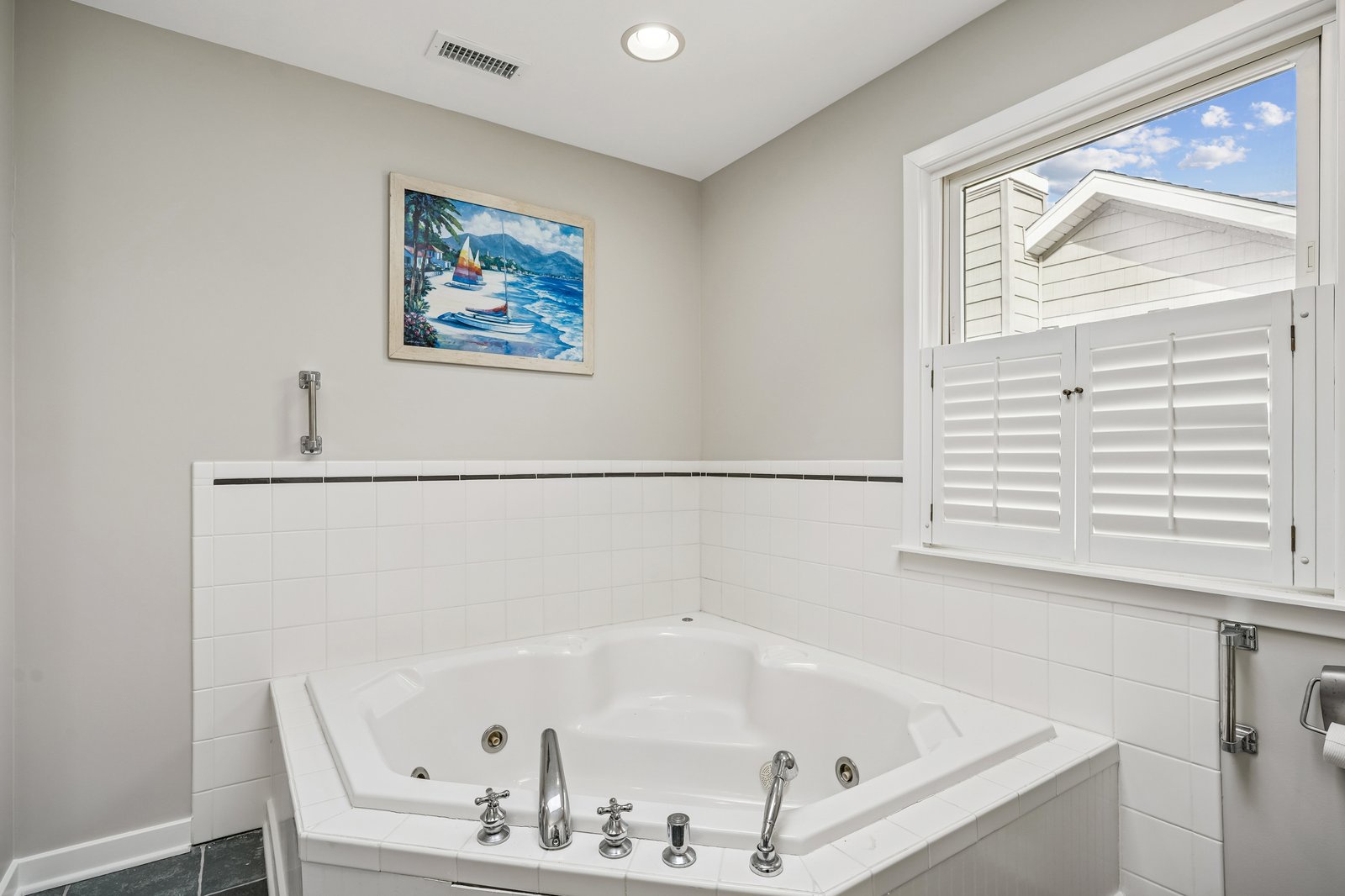 Unwind in your private jetted tub surrounded by elegant tile and coastal artwork, creating the perfect sanctuary for relaxation.