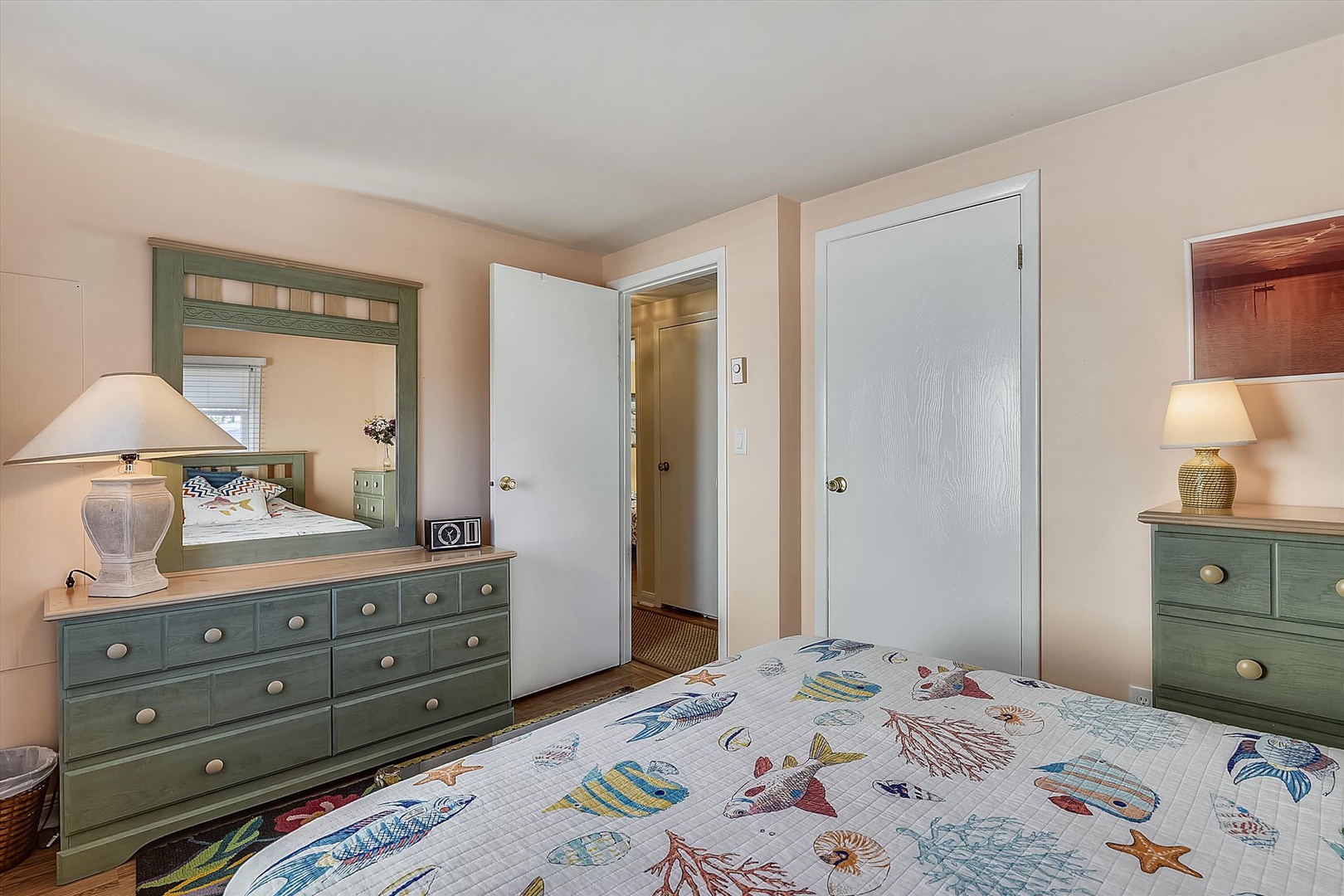 Unwind in your coastal-themed bedroom, featuring charming sage-green furnishings, warm lighting, and cheerful nautical bedding that invites restful seaside dreams.