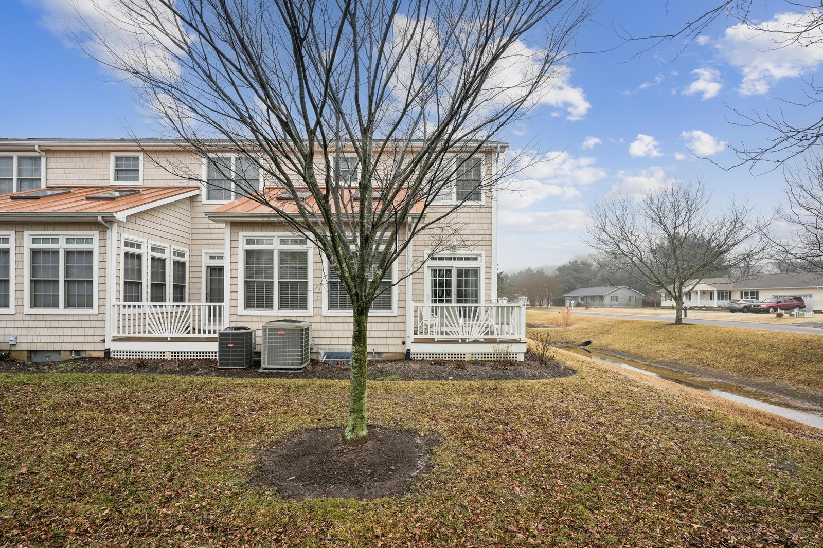 Charming townhome exterior featuring a welcoming front porch and peaceful neighborhood setting, perfect for a relaxing getaway.