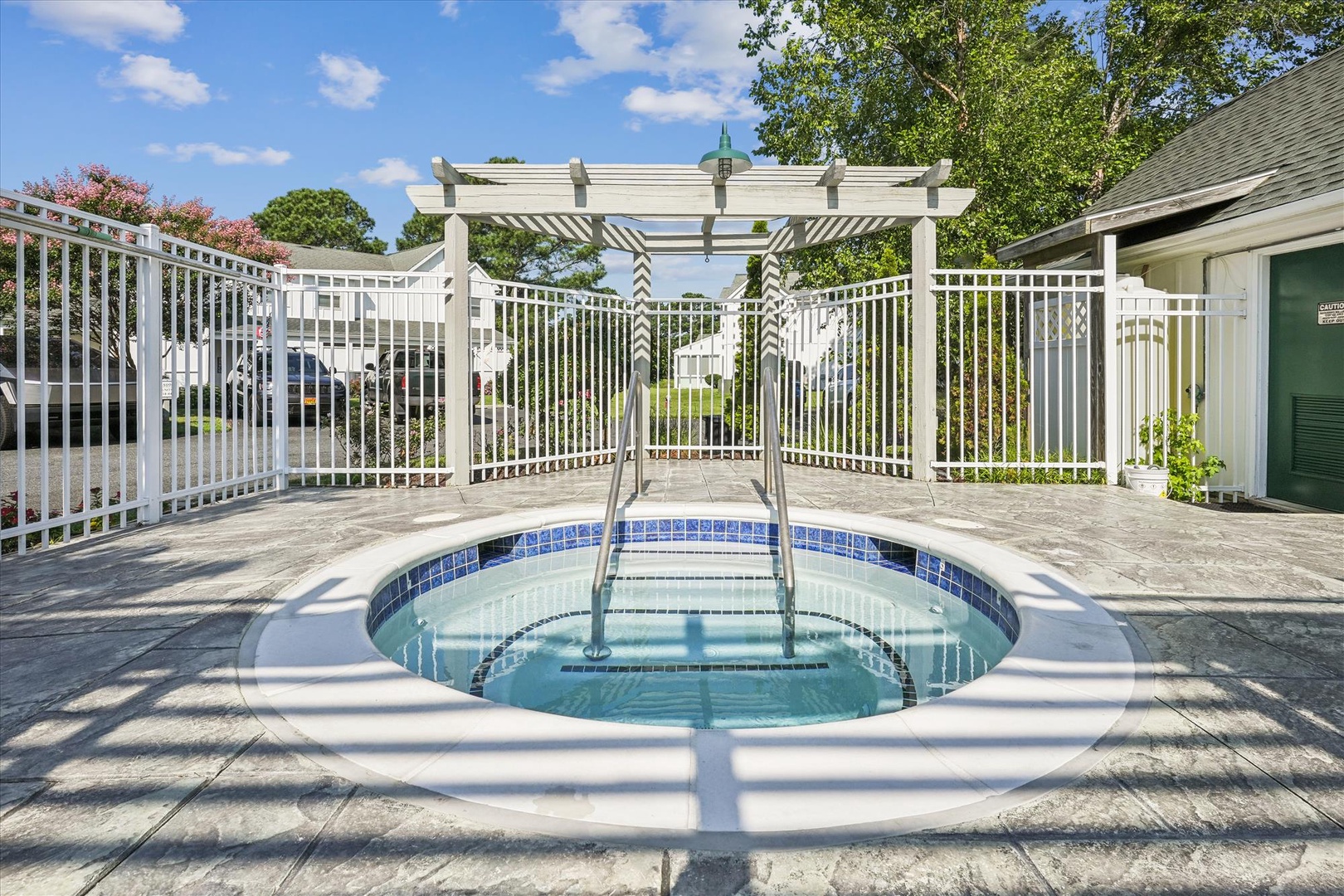 Step into the built-in hot tub, where warm bubbles soothe your muscles under a sunny sky framed by elegant white pergolas and lush greenery.