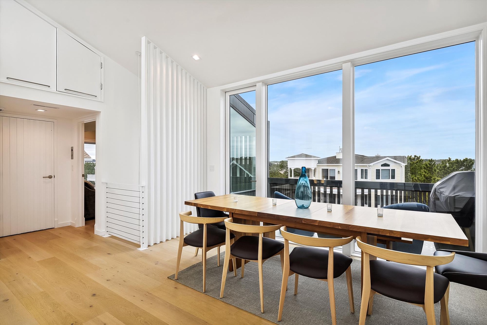 Gather around this modern dining table bathed in natural light. Large windows frame peaceful neighborhood views while you enjoy meals together in this bright, inviting space.