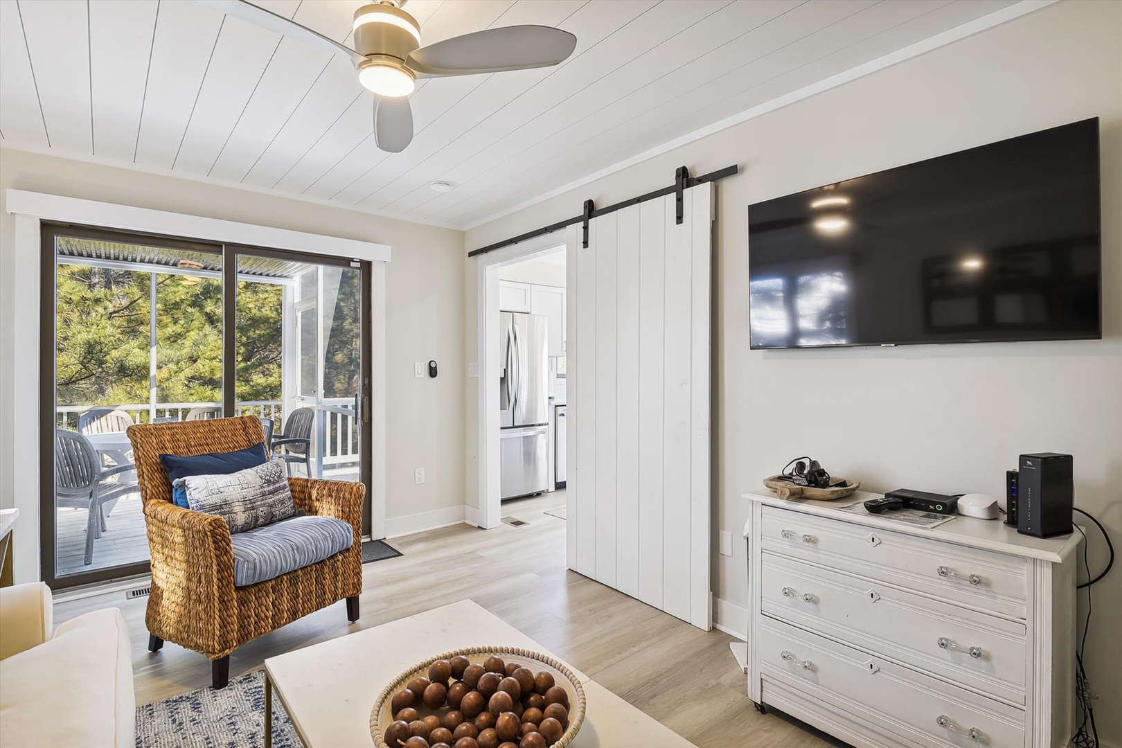 Relax in your bright living area with sliding barn door, modern ceiling fan, and direct access to your private balcony overlooking lush greenery.
