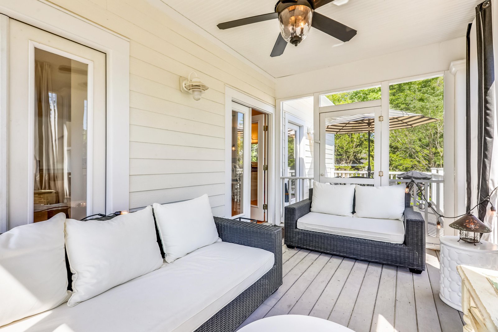 Step onto your covered porch and sink into plush outdoor seating where you can unwind beneath the ceiling fan and soak in the lush, leafy surroundings just beyond the railing.
