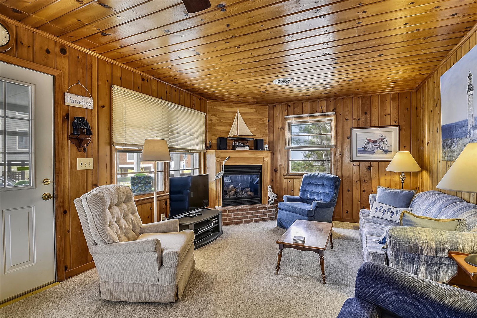 Unwind in your cozy living room, complete with a warm fireplace, plush seating, and charming wood-paneled walls that create the perfect retreat after a day of adventure.