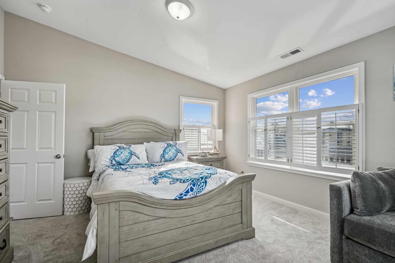 Relax in your peaceful bedroom with coastal-themed bedding and bright windows offering beautiful city views.