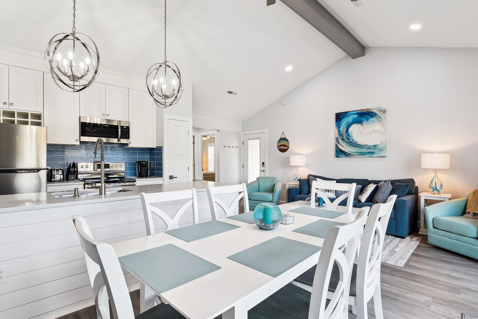 Relax in this bright, open-concept space where coastal hues and vaulted ceilings create an airy retreat. Your dining table overlooks a stylish living area and sleek kitchen—perfect for unwinding after beach adventures.