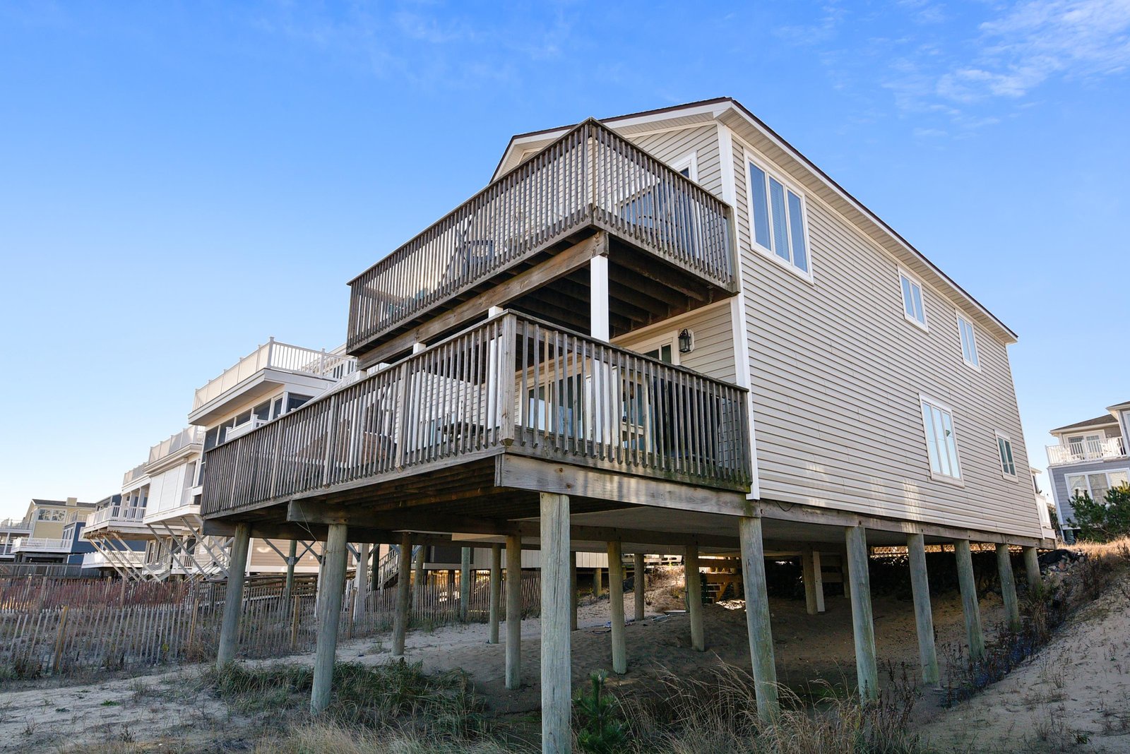 A beachfront property elevated on sturdy pilings sits just steps from the sandy shore, offering direct coastal access and proximity to neighboring beach homes.