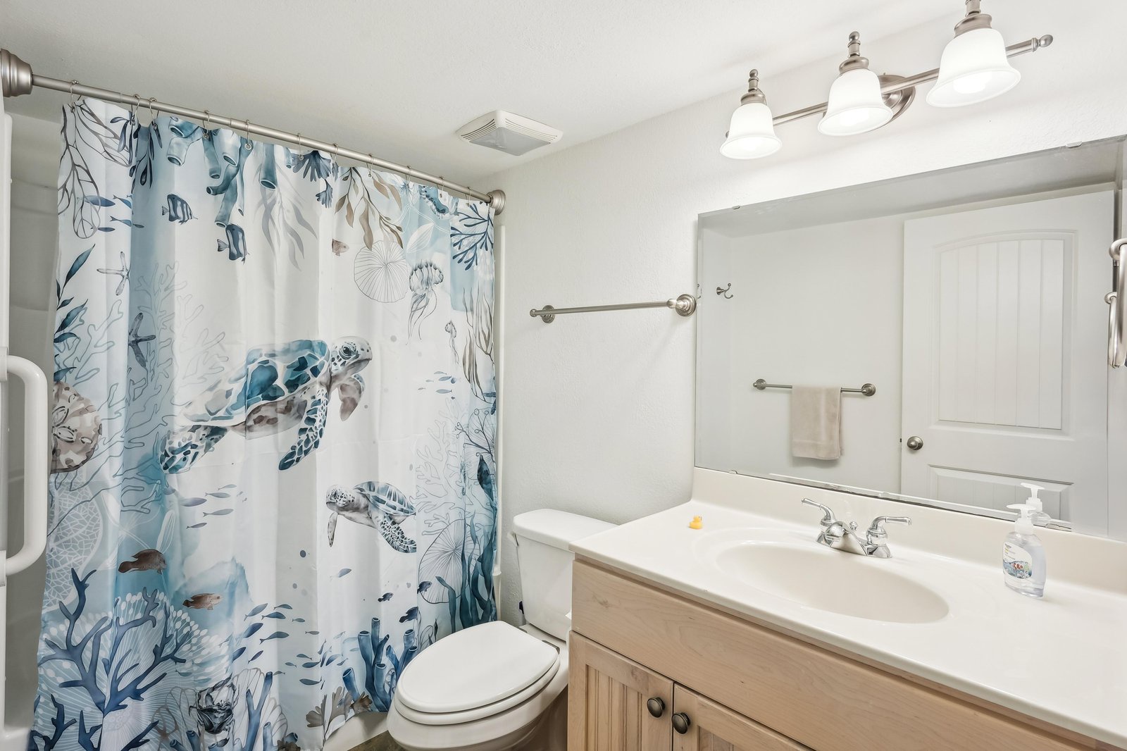 Freshen up in your coastal-themed bathroom, complete with a cheerful sea turtle shower curtain and crisp white vanity. Your retreat awaits with soft towels and coastal charm.