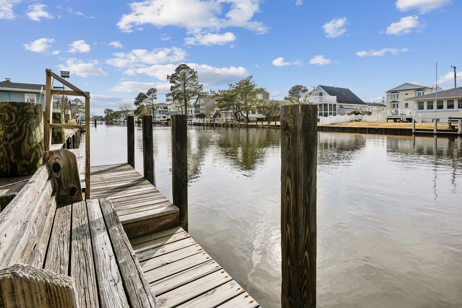 Waterfront dock extends into calm waters, surrounded by charming coastal homes and peaceful marina atmosphere.