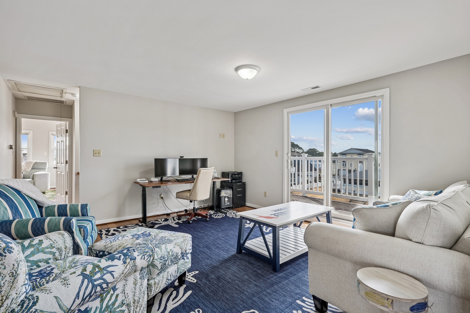 Unwind in your bright living room with coastal-themed decor, comfortable seating, and balcony access for fresh air.