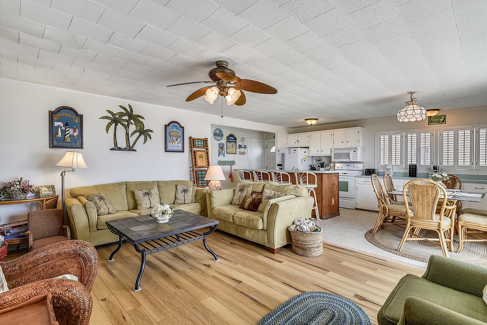 Picture yourself unwinding in your spacious coastal-themed retreat, where warm wood floors, comfortable seating, and breezy tropical décor invite you to relax. Your fully equipped kitchen awaits.