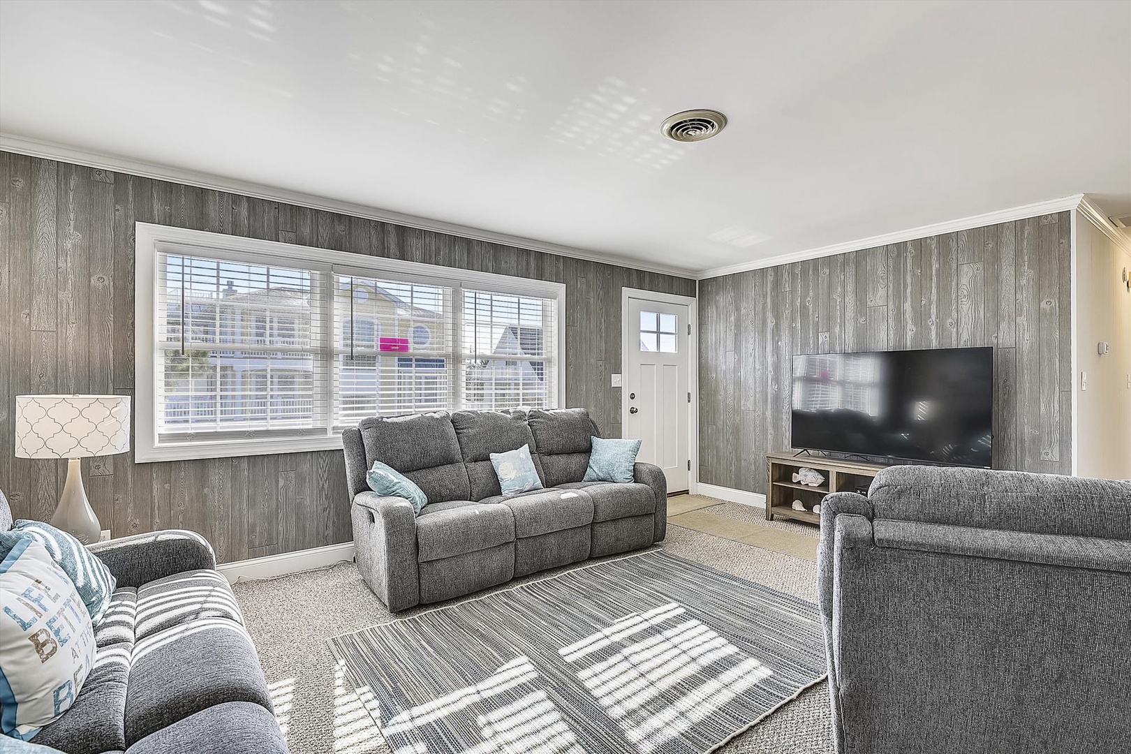Sink into plush gray sofas and unwind in your light-filled living room, where the TV awaits movie nights and the windows frame peaceful neighborhood views.