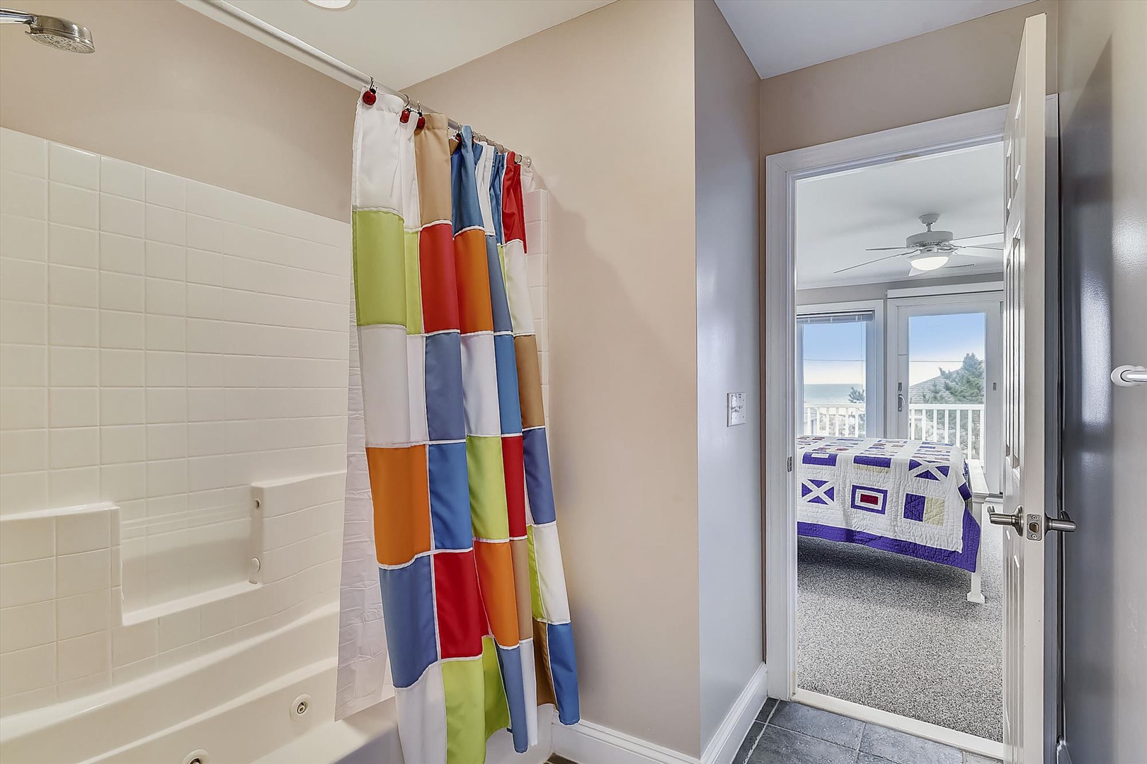 Fresh, cheerful bathroom with a cozy tub-shower combo, colorful curtain, and clean tile—your space to unwind after days at the beach or exploring town.