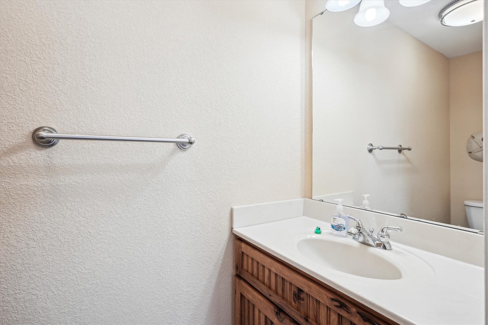 Your private bathroom features a clean vanity with fresh countertop space, a large mirror, and bright lighting to help you feel refreshed.