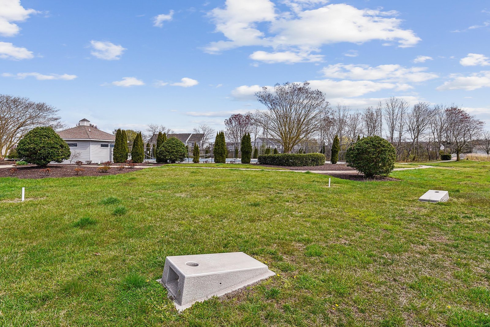 The property is set within a well-maintained neighborhood, featuring expansive green lawns, mature trees, and manicured landscaping that create a peaceful residential setting.