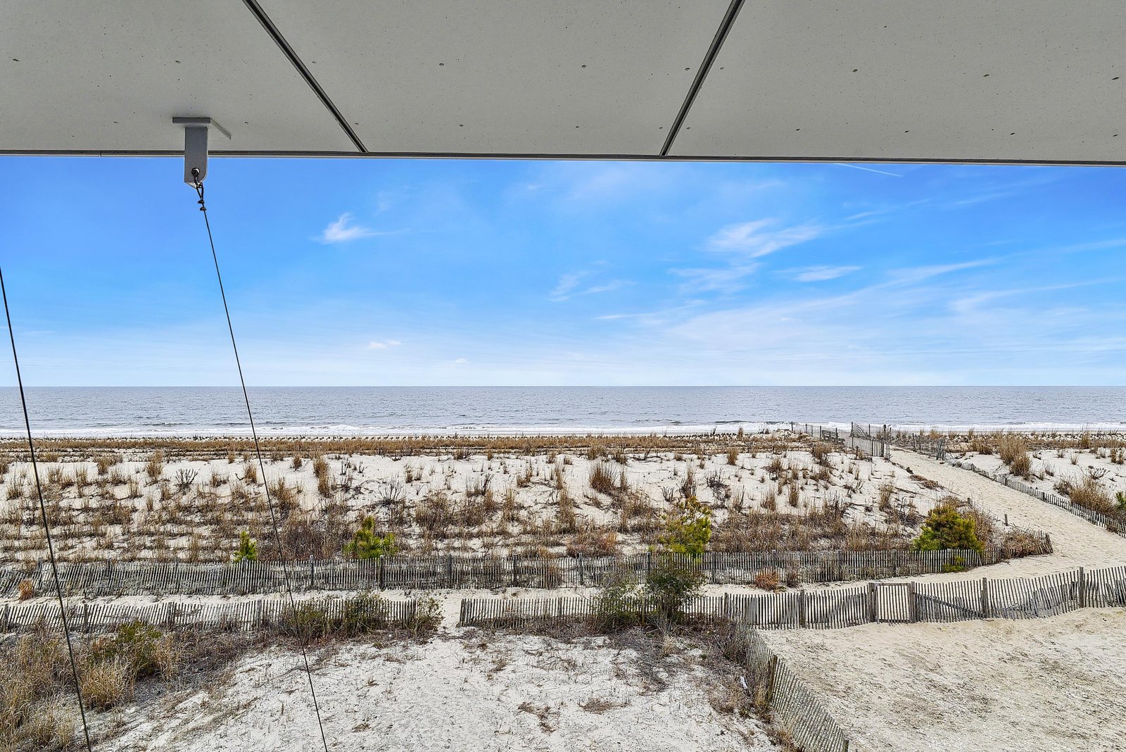 Expansive coastal scenery stretches before you, with protected dunes and beach grasses leading to the open horizon where sea meets sky.