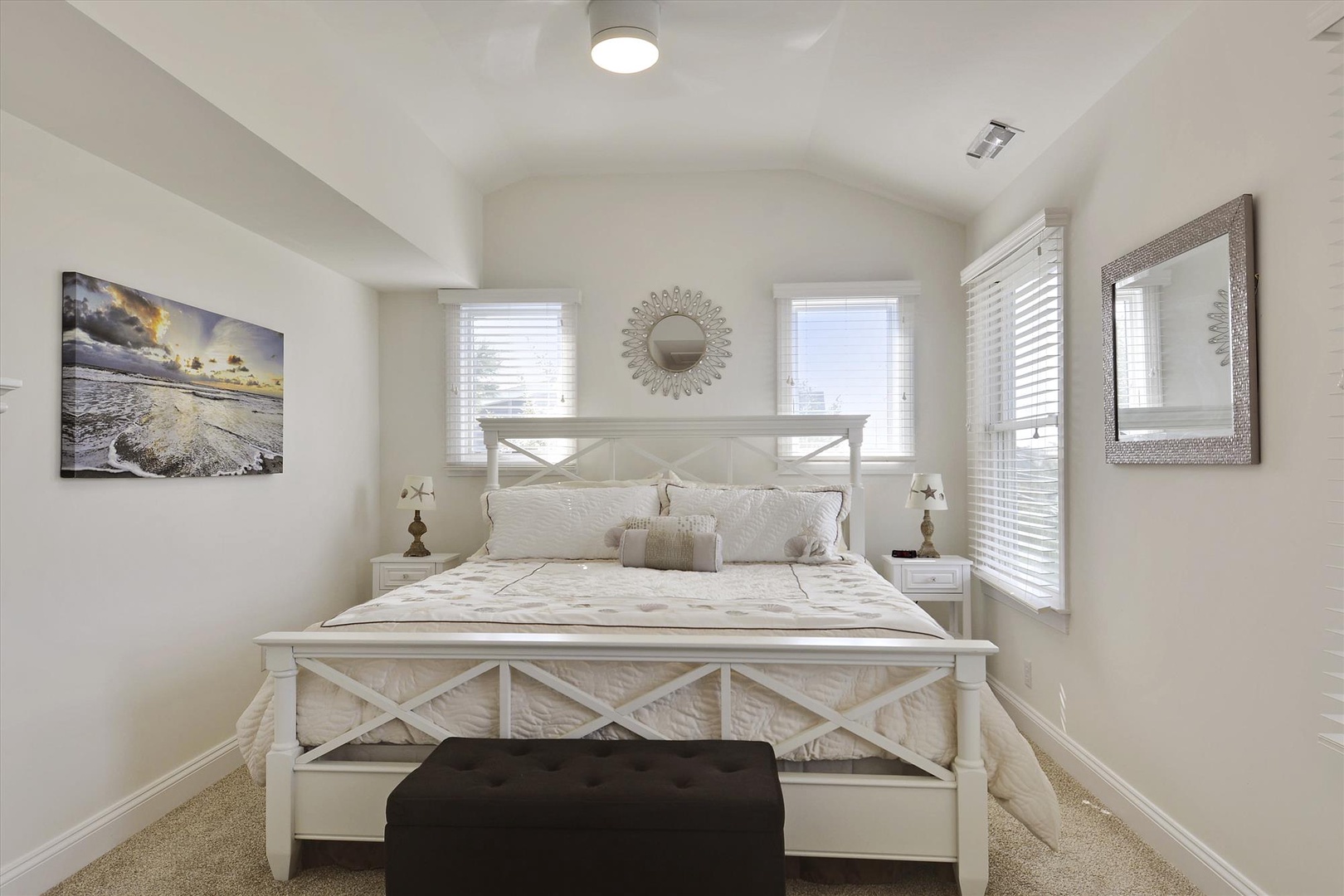 Sink into comfort in your serene bedroom, where crisp white linens and coastal artwork create the perfect retreat after beach days.