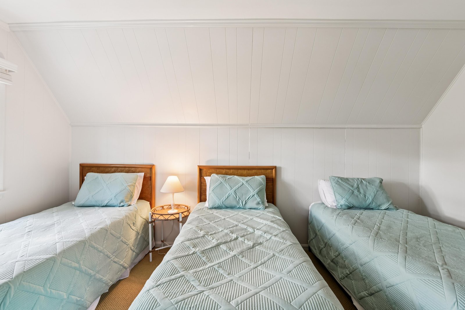 Your peaceful retreat awaits with three cozy beds dressed in soothing aqua linens, perfectly arranged under charming shiplap ceilings that add coastal character to your restful escape.