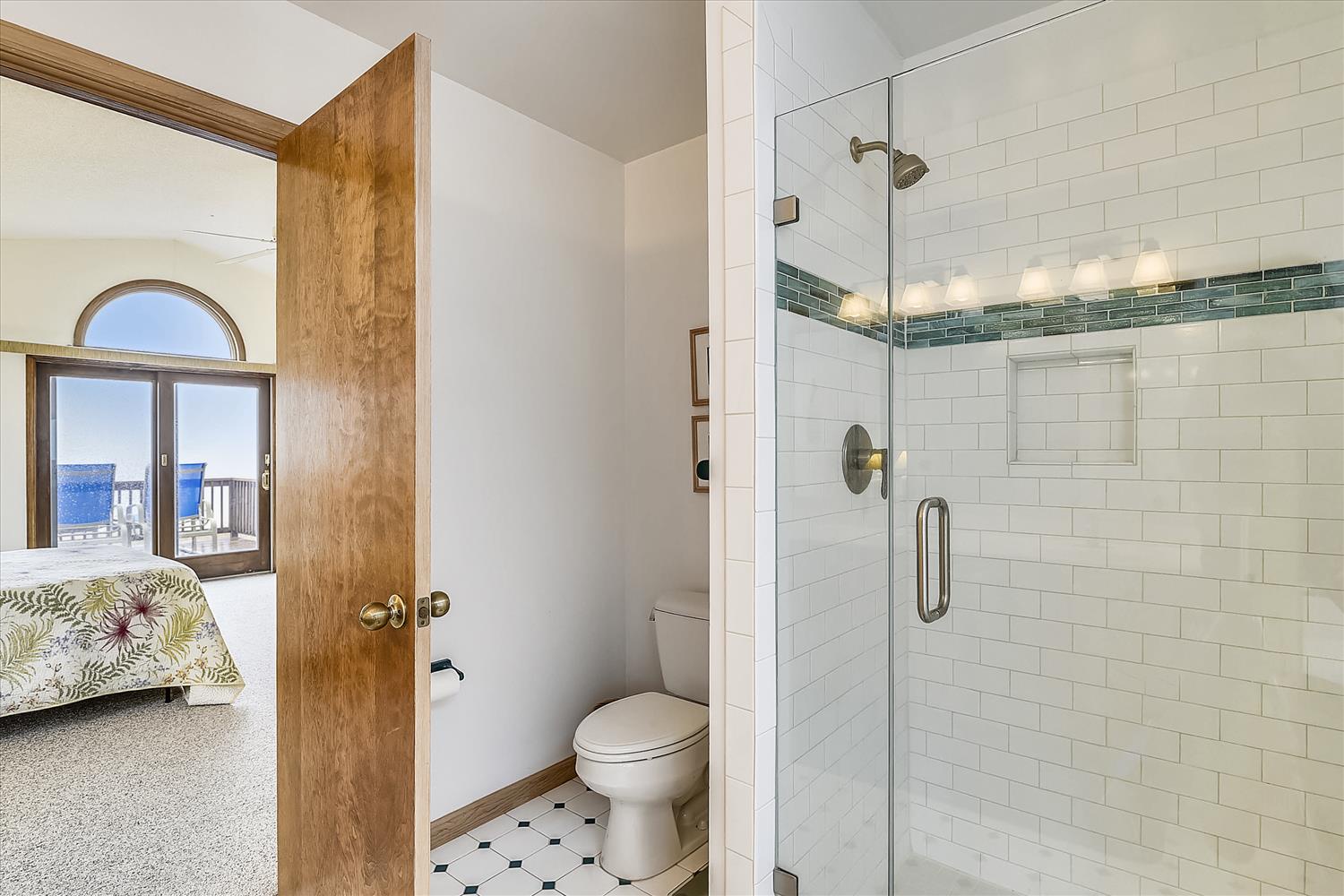 Step into your stylish en-suite bathroom featuring a gorgeous walk-in shower with subway tiles and soothing green accents for your refreshing daily routine.