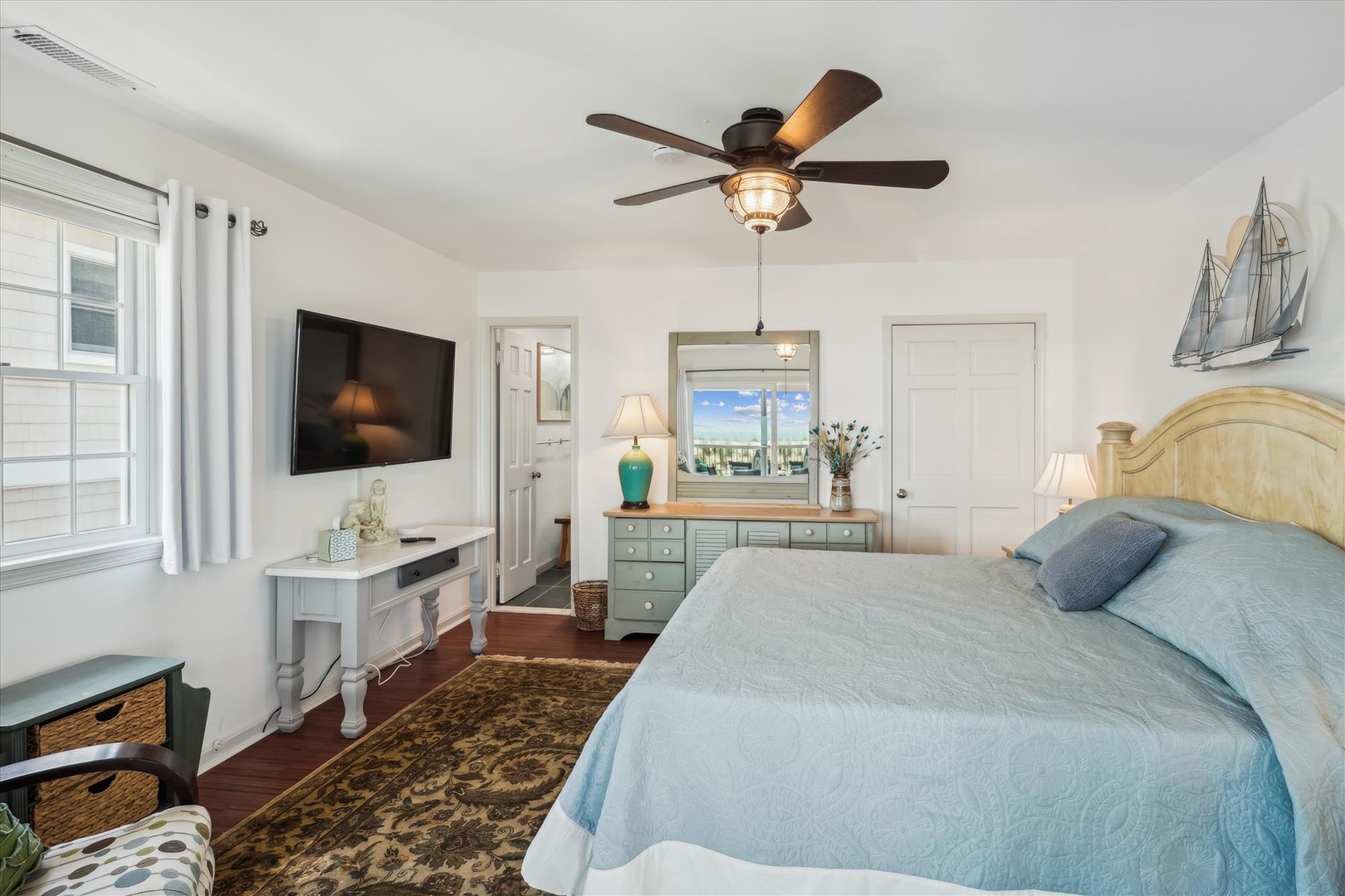 Unwind in your serene coastal retreat with a plush bed, ceiling fan, and nautical touches that invite you to relax in style and comfort.