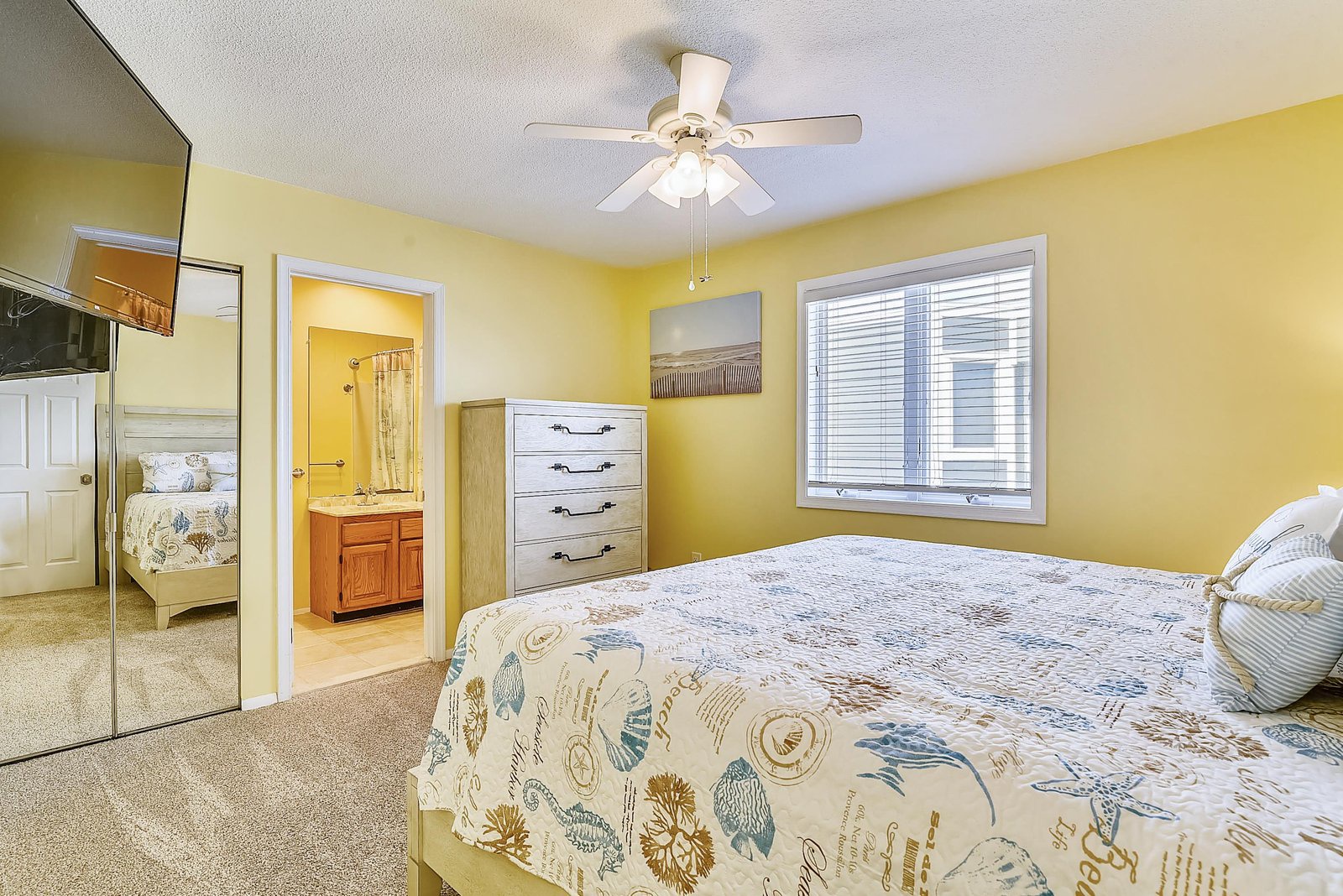 Bright, cheerful bedroom with ensuite access and a soft coastal palette. Drift off in comfort under the gentle hum of your ceiling fan.