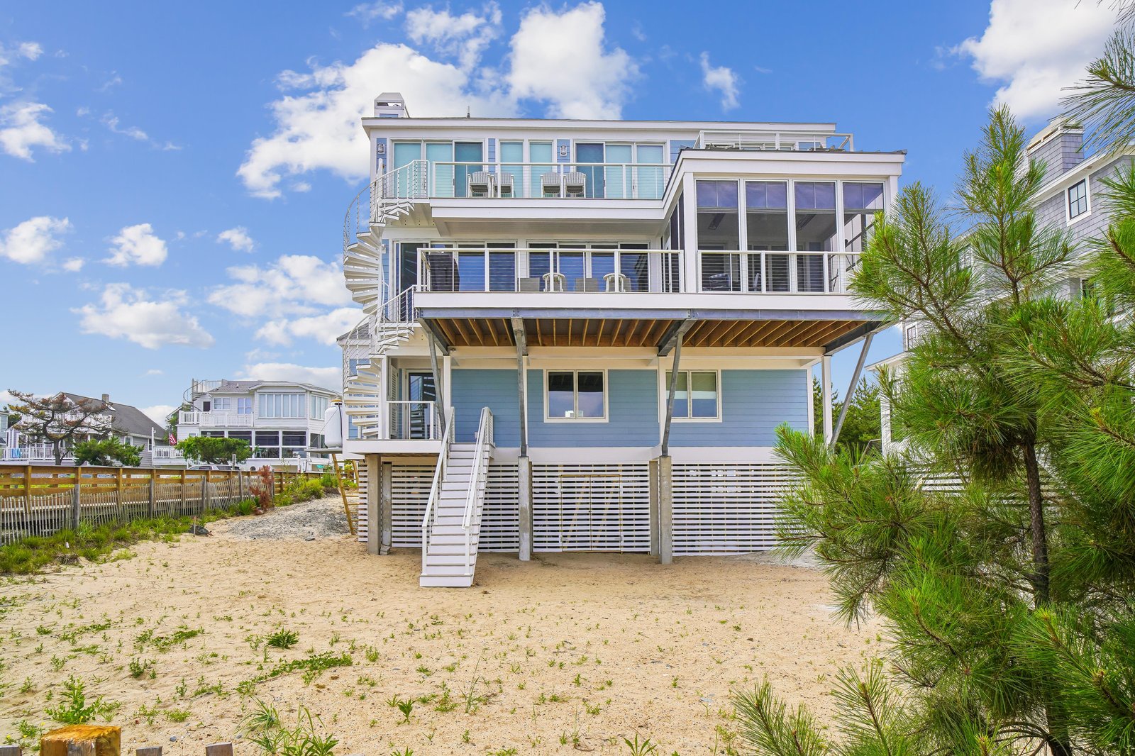 This modern beachfront home sits directly on the sand with multiple balconies overlooking the shore. The property features an exterior staircase and elevated design, offering unobstructed beach access just steps from your door.