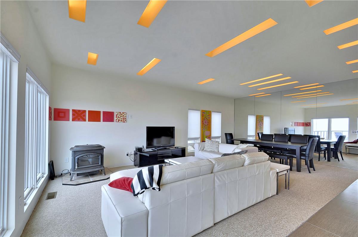 Sink into plush seating beneath glowing amber accents that wash the ceiling in warmth. Your entertainment hub awaits with a cozy fireplace nearby, perfect for unwinding after exploring.