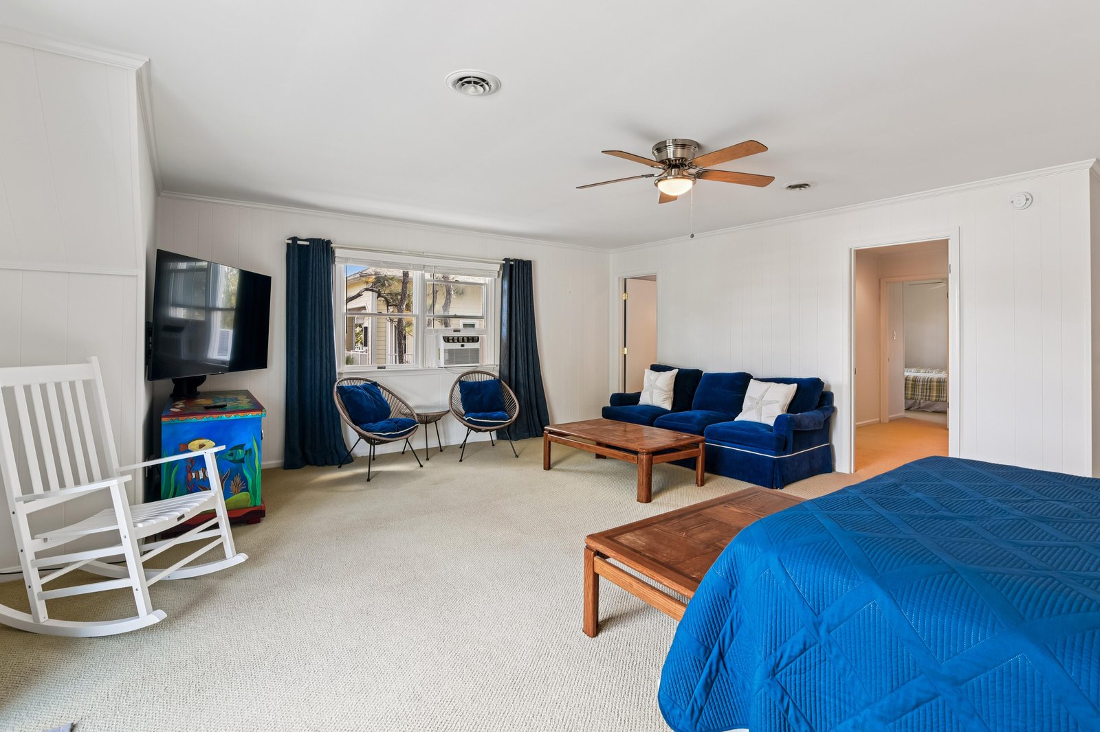 Relax in your spacious suite with plush blue seating, a cozy rocking chair, and a ceiling fan to keep you comfortable—all with peaceful views just outside your window.