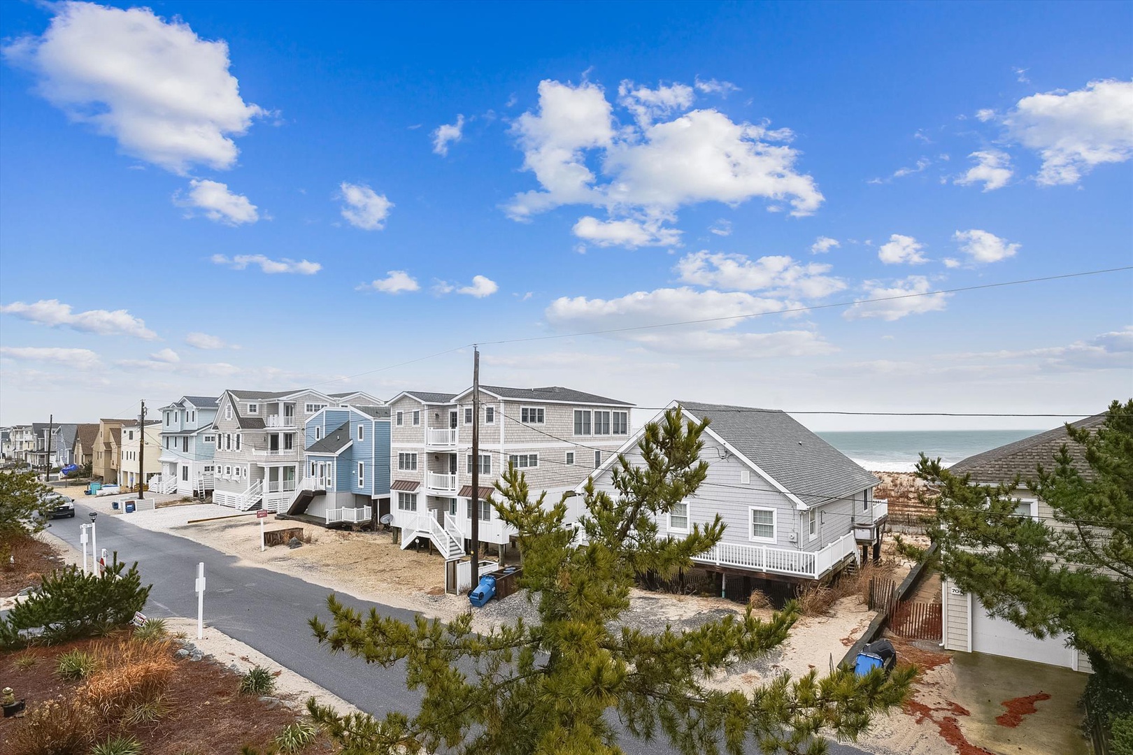 Coastal residential neighborhood featuring beachfront vacation homes with ocean access, sandy shores, and serene coastal living environment under clear blue skies.