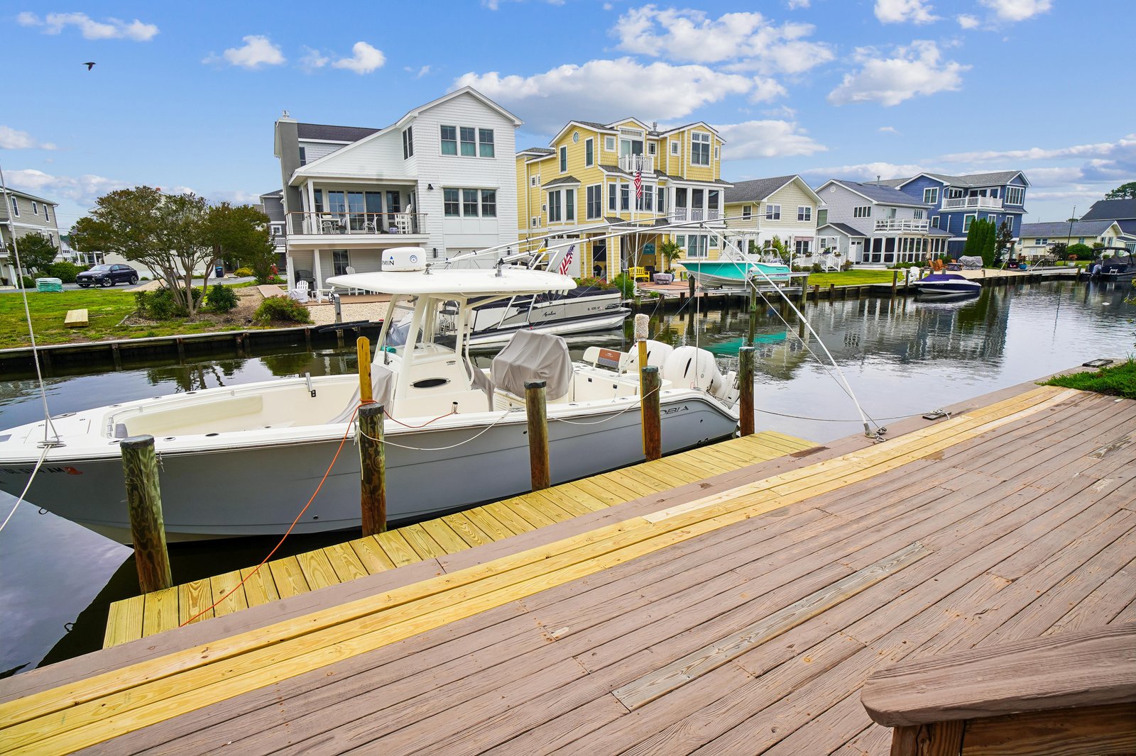This waterfront rental features private dock access with boat slips in a peaceful canal neighborhood, surrounded by colorful coastal homes and palm trees.