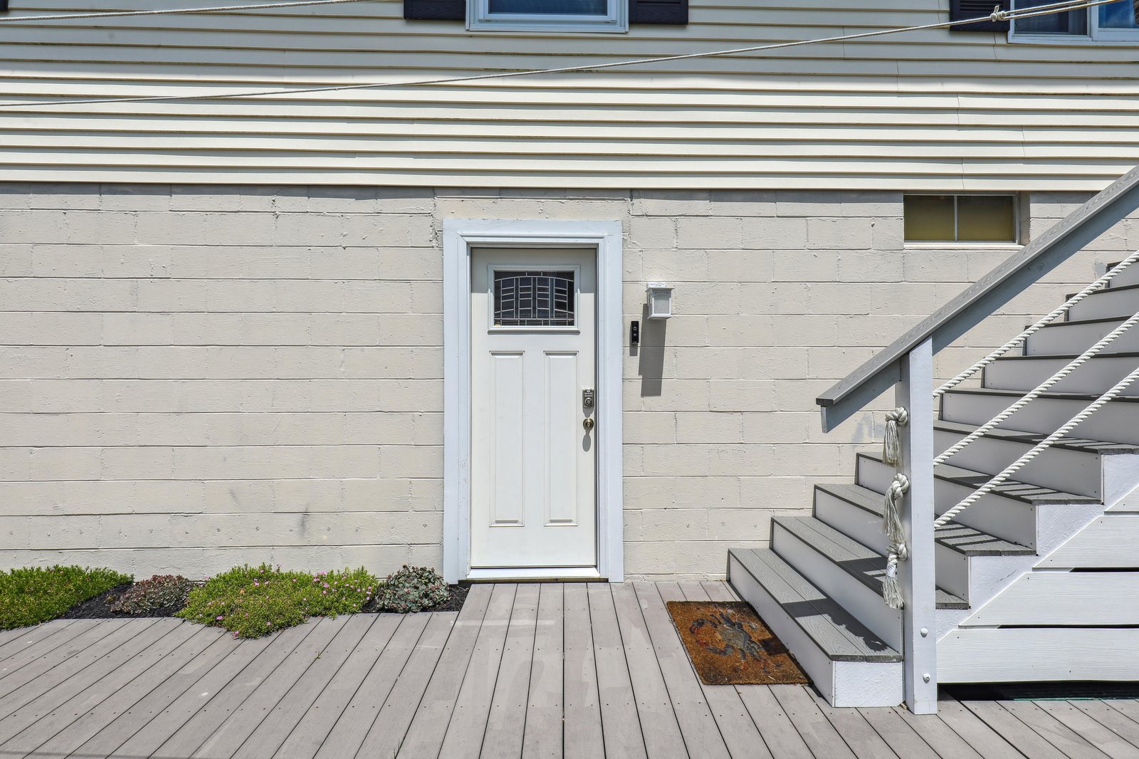 The property's exterior features a separate ground-level entrance with clean white siding and an exterior staircase.
