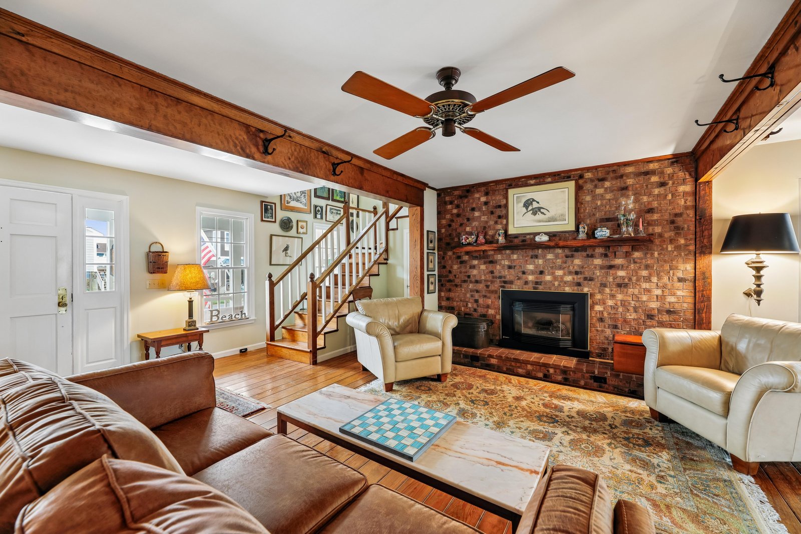 Relax in your spacious living room featuring a cozy brick fireplace, rustic wooden beams, and comfortable seating perfect for gathering after a day of exploring.