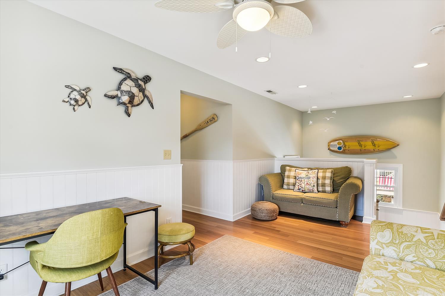 Sink into the plush seating and let the coastal vibes wash over you in this inviting living space, complete with charming beach-inspired décor and warm wood floors underfoot.