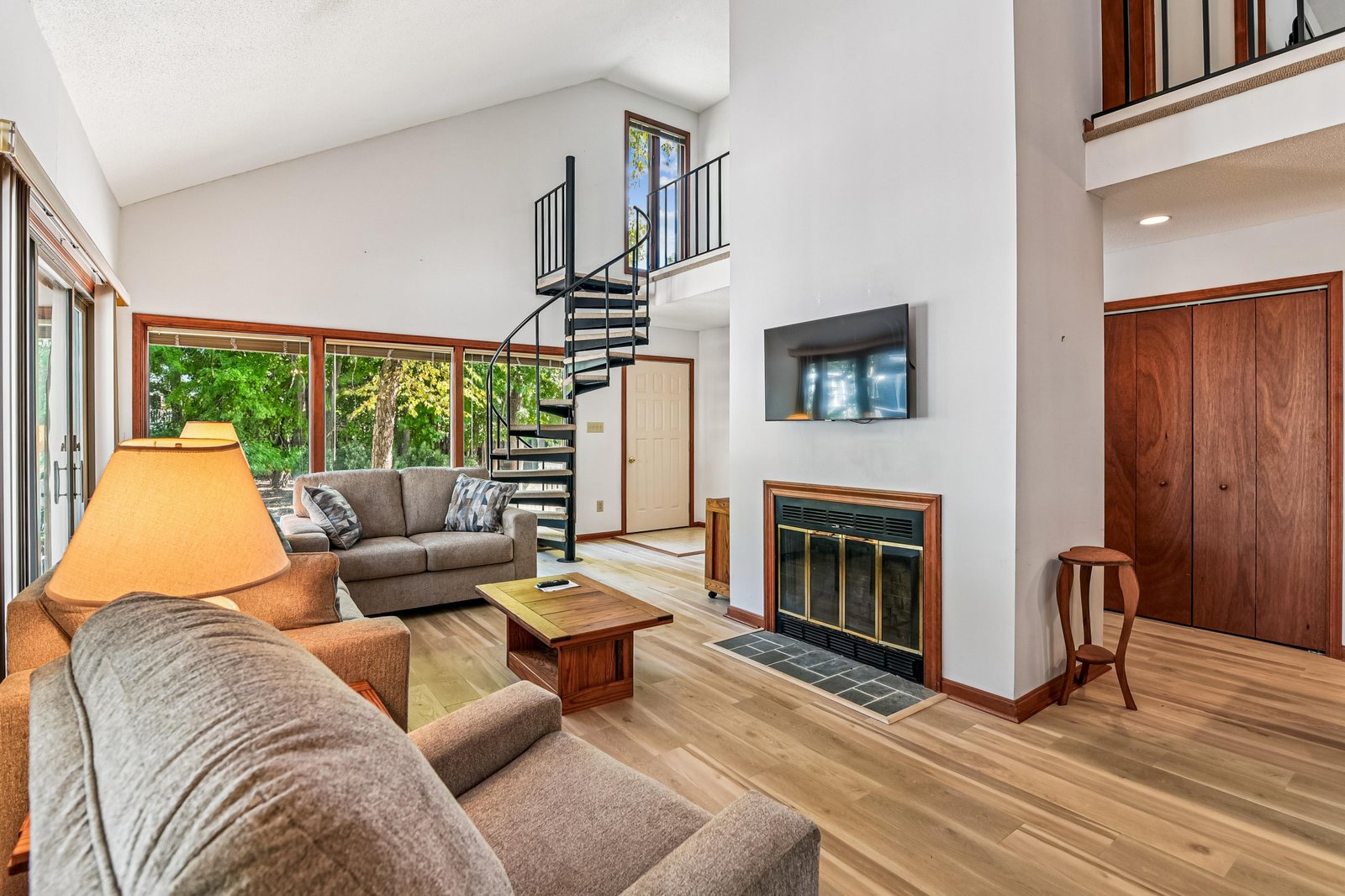 Settle into your bright, spacious living room where soaring ceilings and floor-to-ceiling windows frame lush forest views. Curl up by the cozy fireplace or unwind on the plush sofas after a day of adventure.