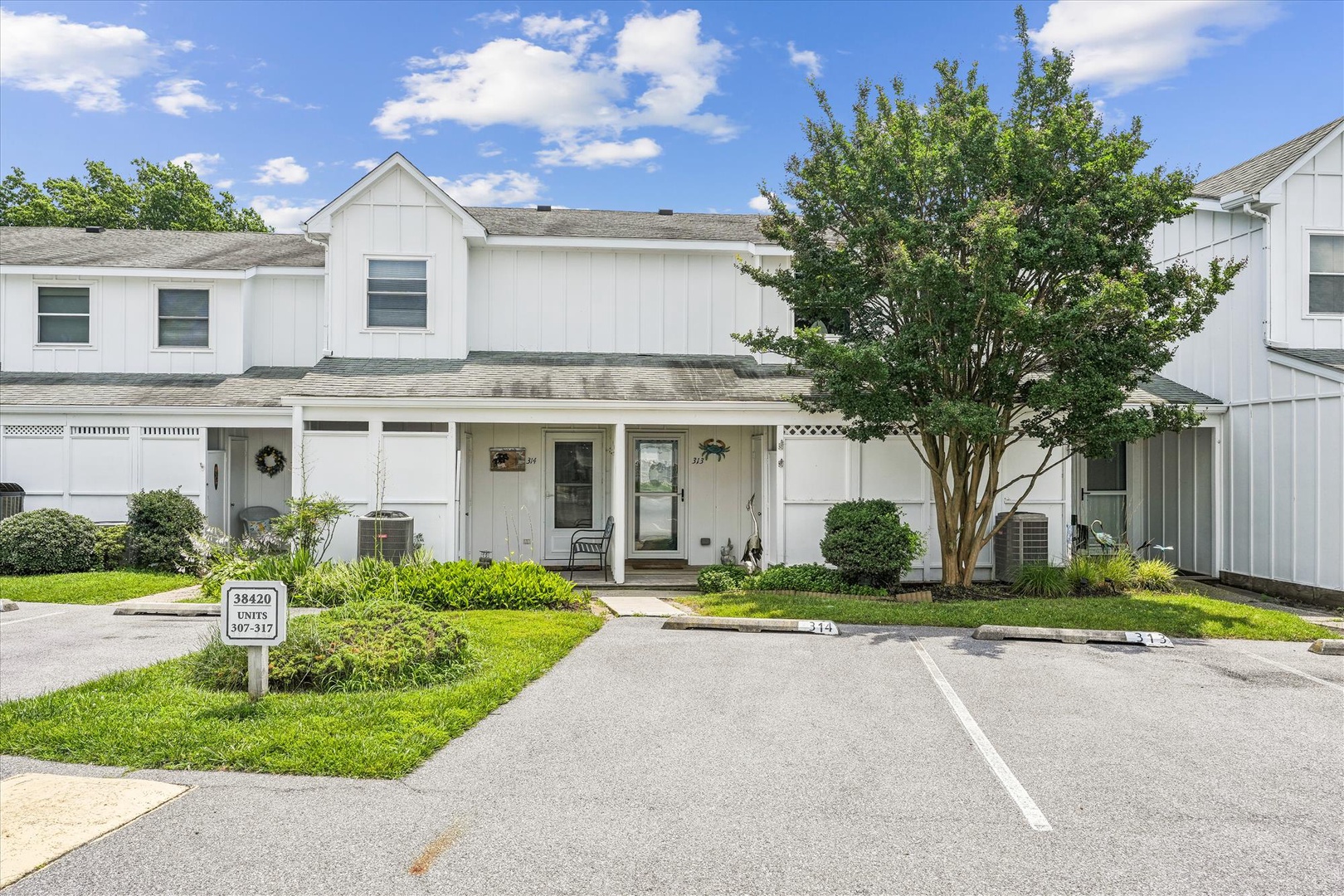 Clean white townhome exterior with dedicated parking and landscaped grounds in a well-maintained residential complex.