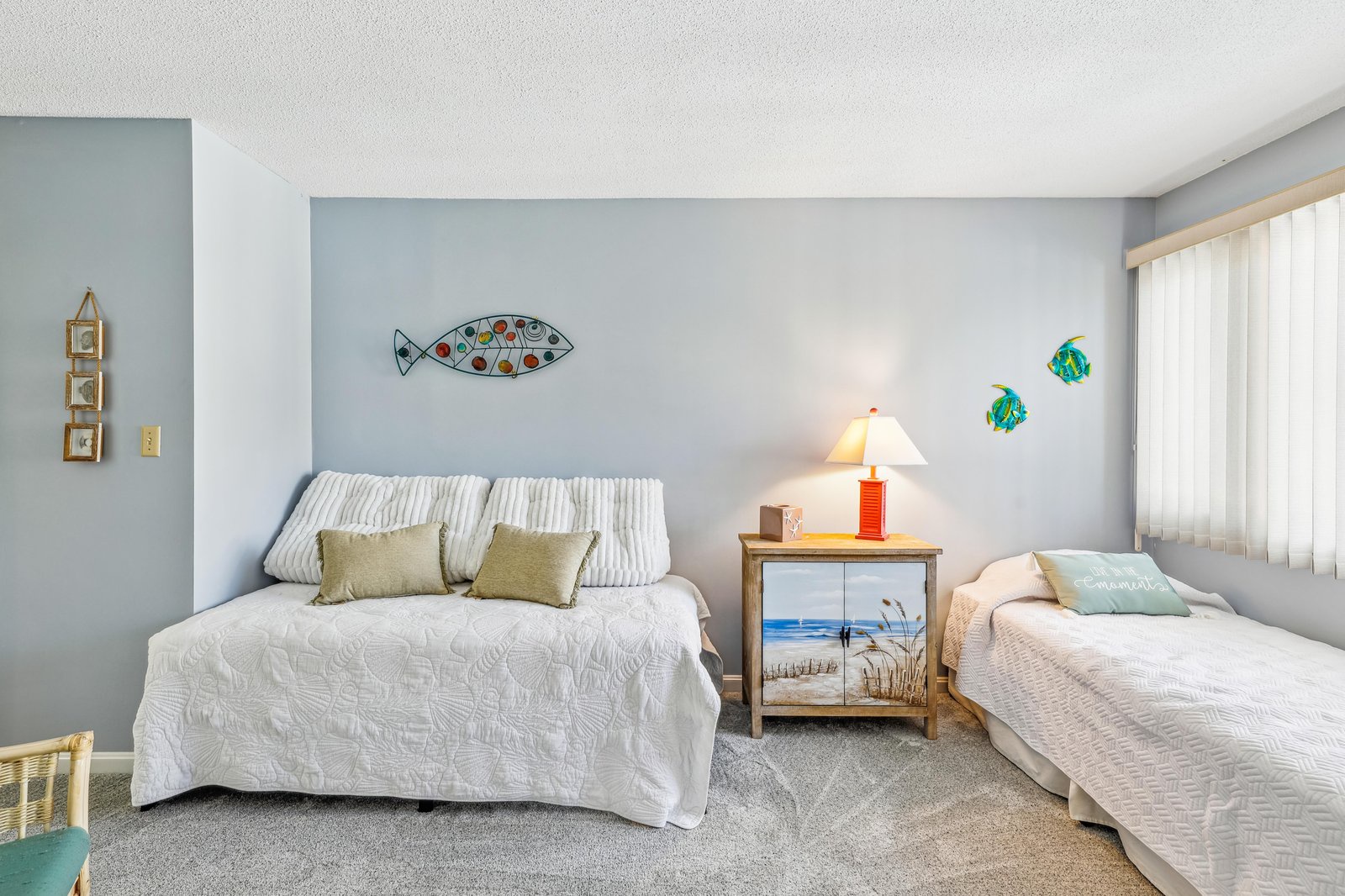 Unwind in your spacious bedroom with coastal charm, featuring two cozy beds dressed in crisp linens and playful beach-themed decor that sets the mood for a peaceful retreat.