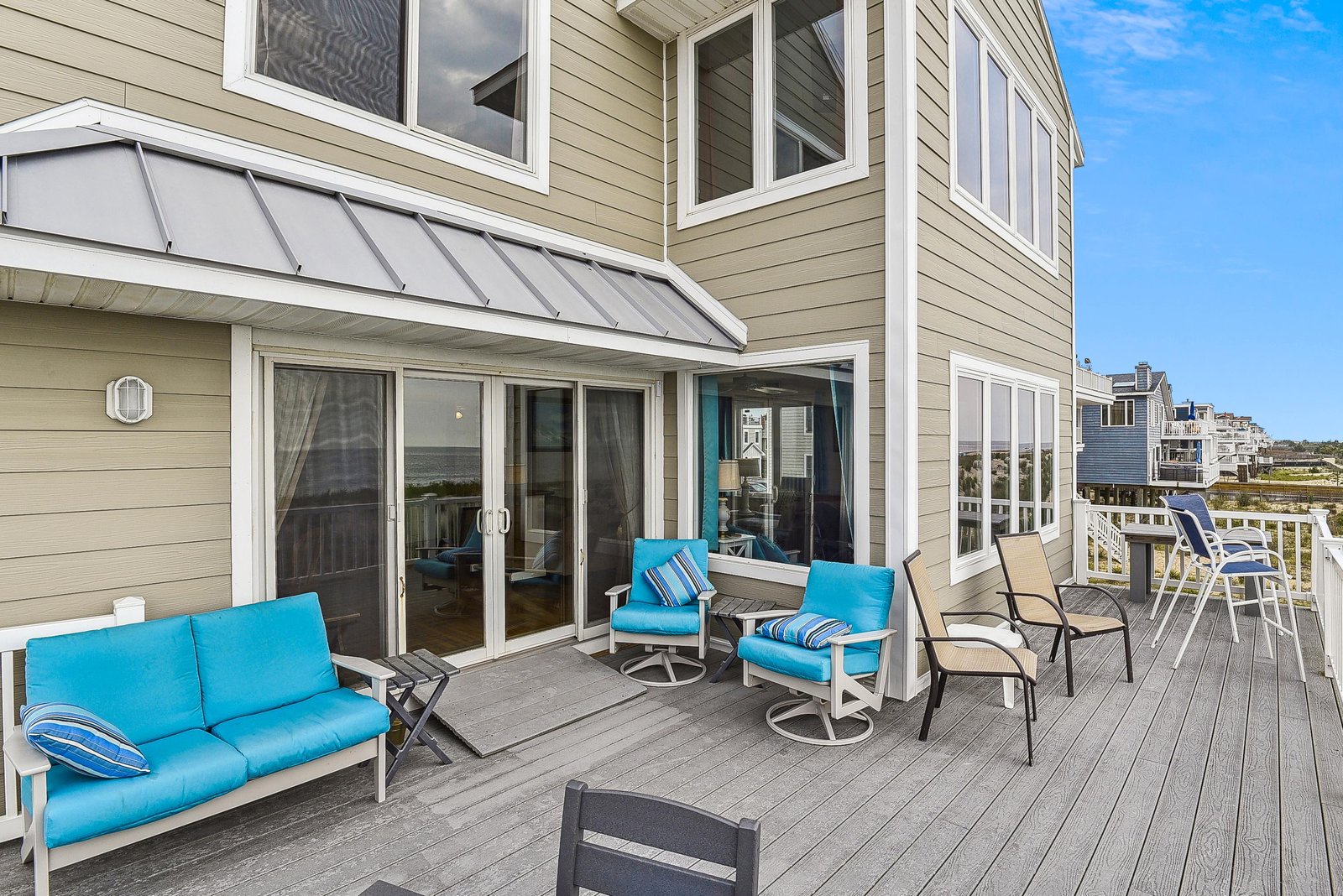 This spacious deck is your coastal retreat, complete with cushioned seating and a shaded awning. The view beyond offers a glimpse of the surrounding neighborhood and horizon—perfect for morning coffee or evening relaxation.