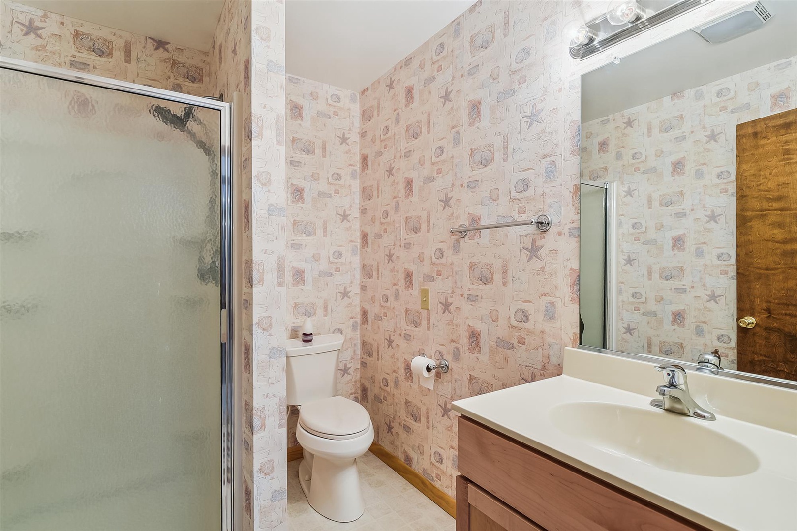 Your private bathroom features a spacious shower, coastal-themed decor, and a vanity with plenty of counter space for your essentials.