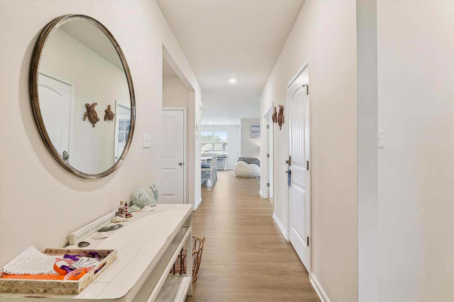 Your serene hallway welcomes you with warm wood floors and coastal touches—charming turtle accents greet you at every turn, setting the tone for relaxation ahead.