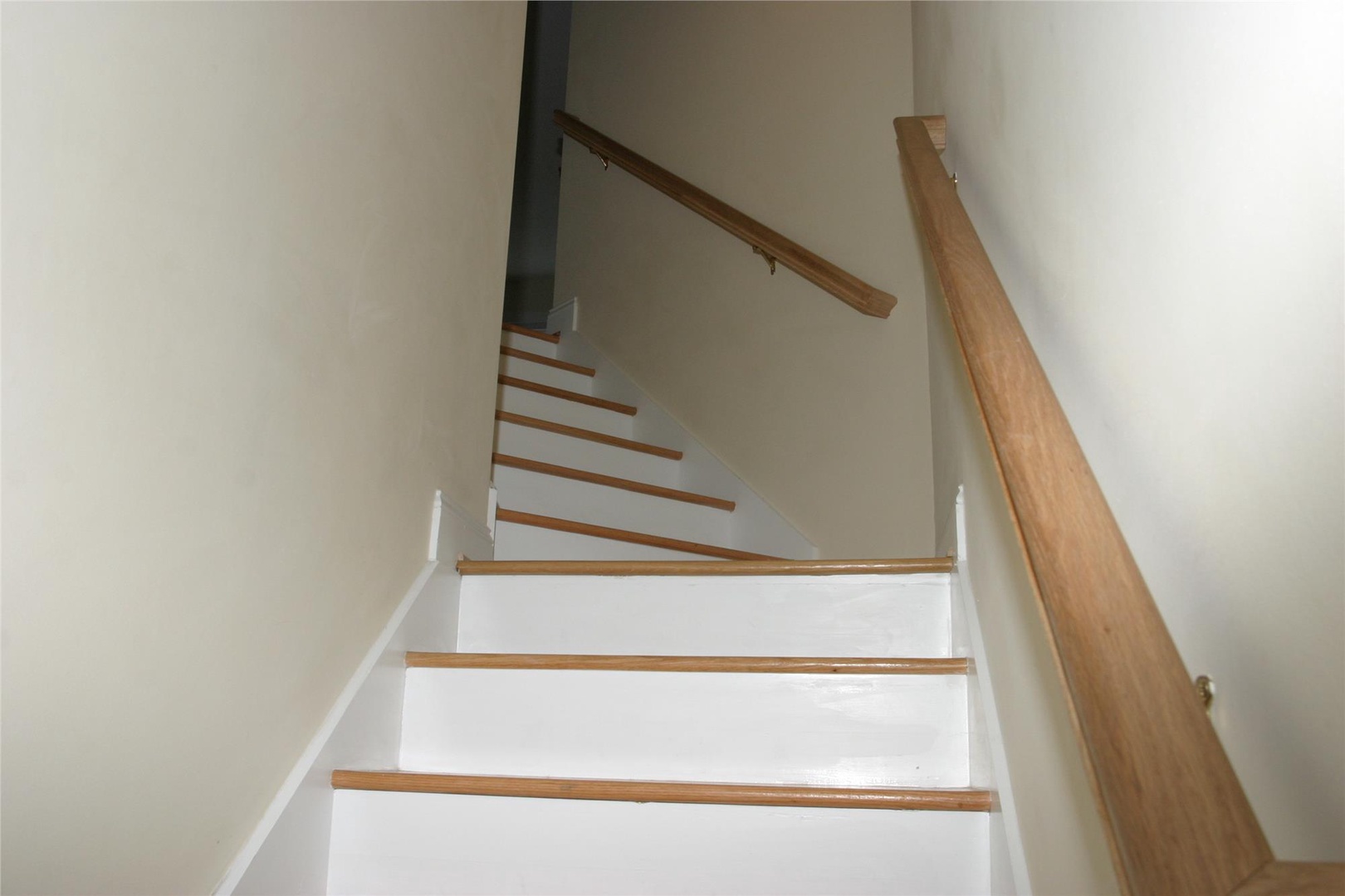 Bright staircase with warm wood accents and smooth white risers connects the floors of the home, offering easy access to all your spaces.