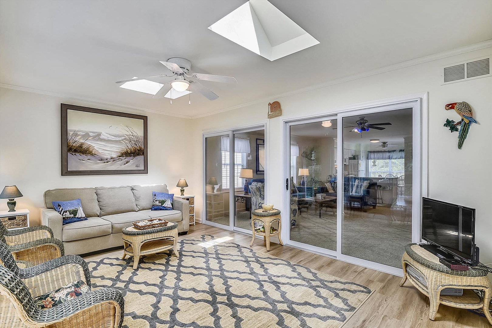 Your sunlit living space features coastal charm with comfy seating, ceiling fan, and skylight flooding the room with natural light—perfect for unwinding after your beach adventures.