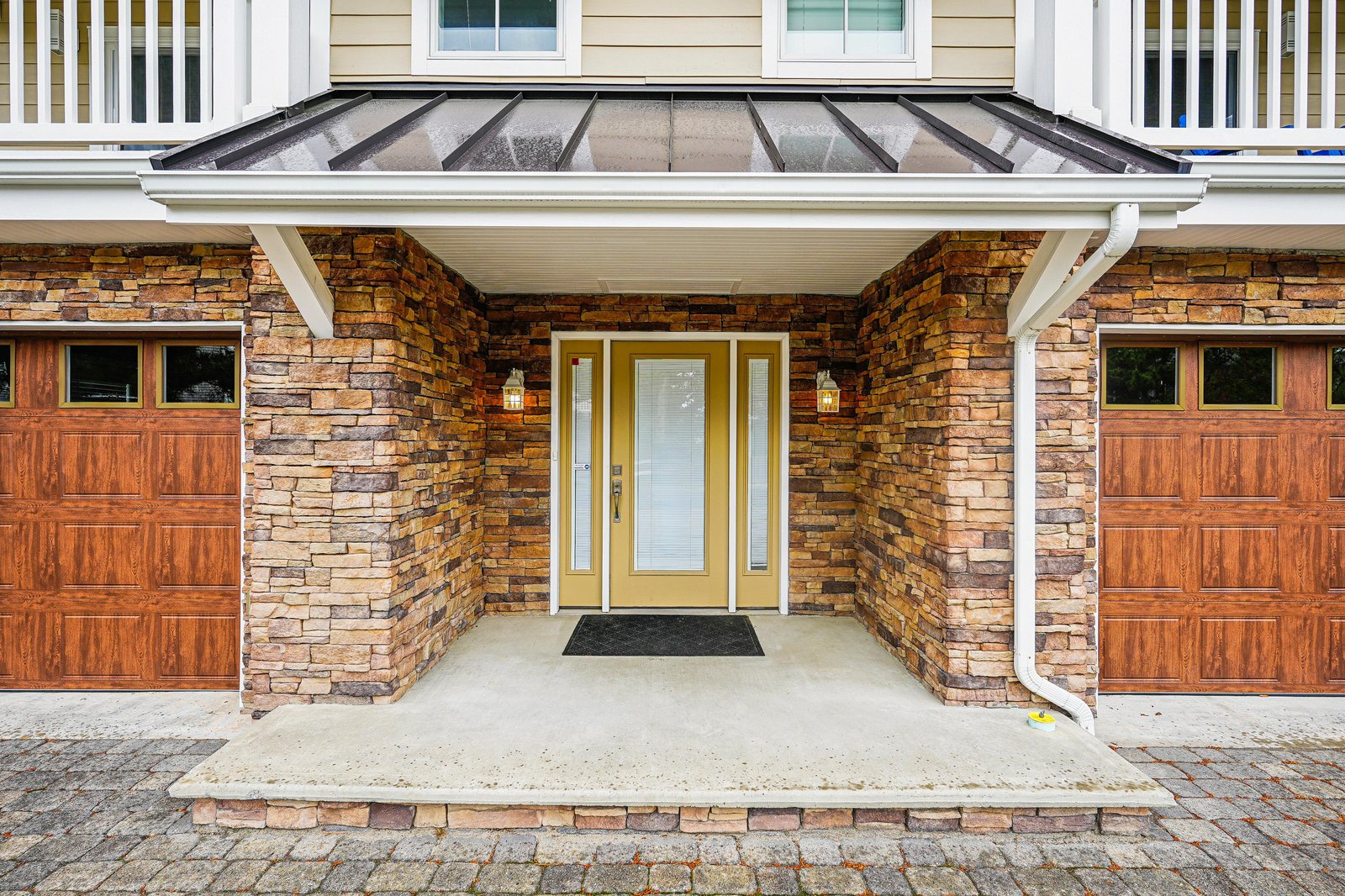 This welcoming entrance features warm stone accents and a covered porch with convenient parking on both sides.