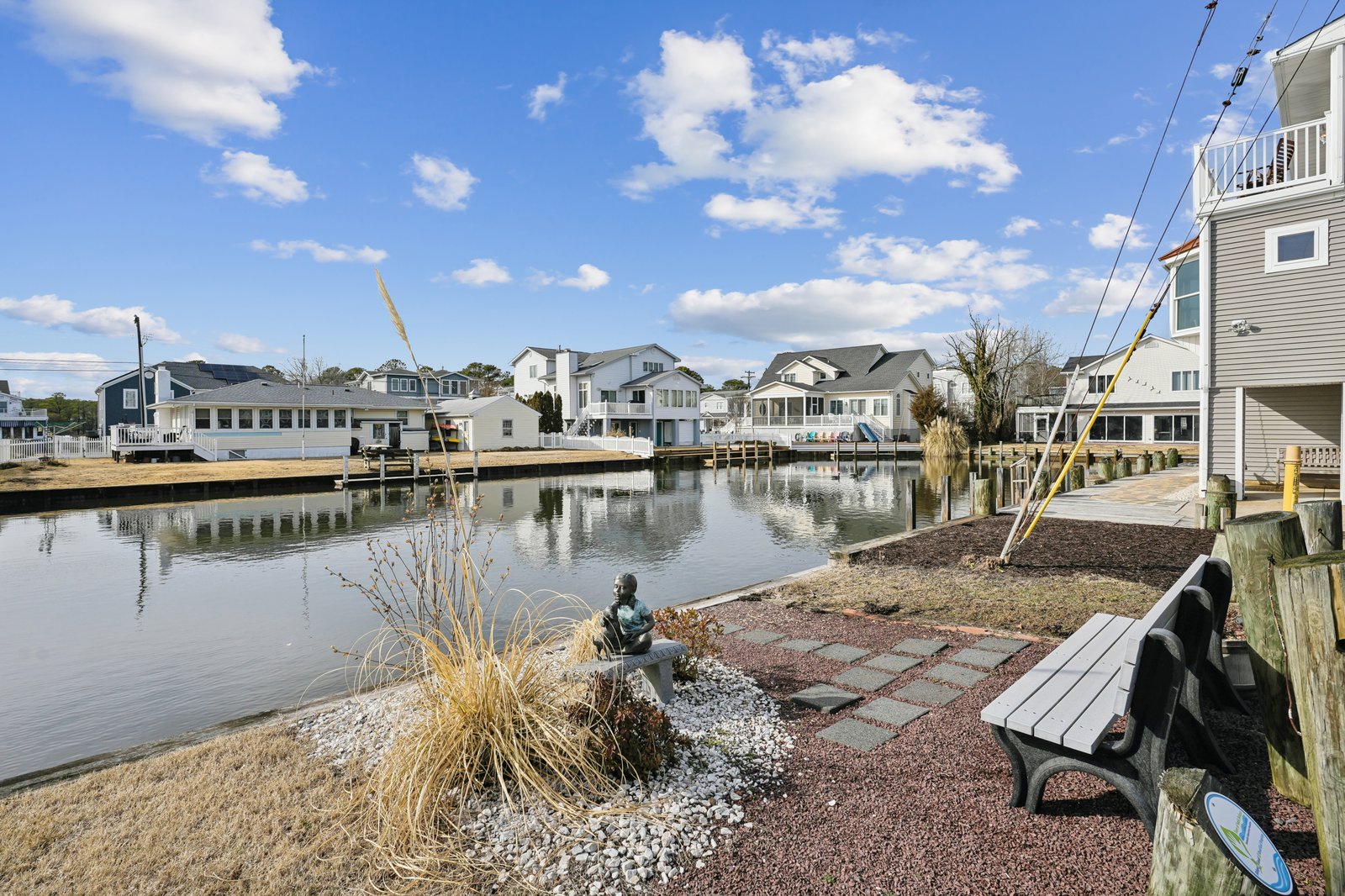 Peaceful waterfront community with charming homes surrounding calm canal waters and a tranquil sitting area.