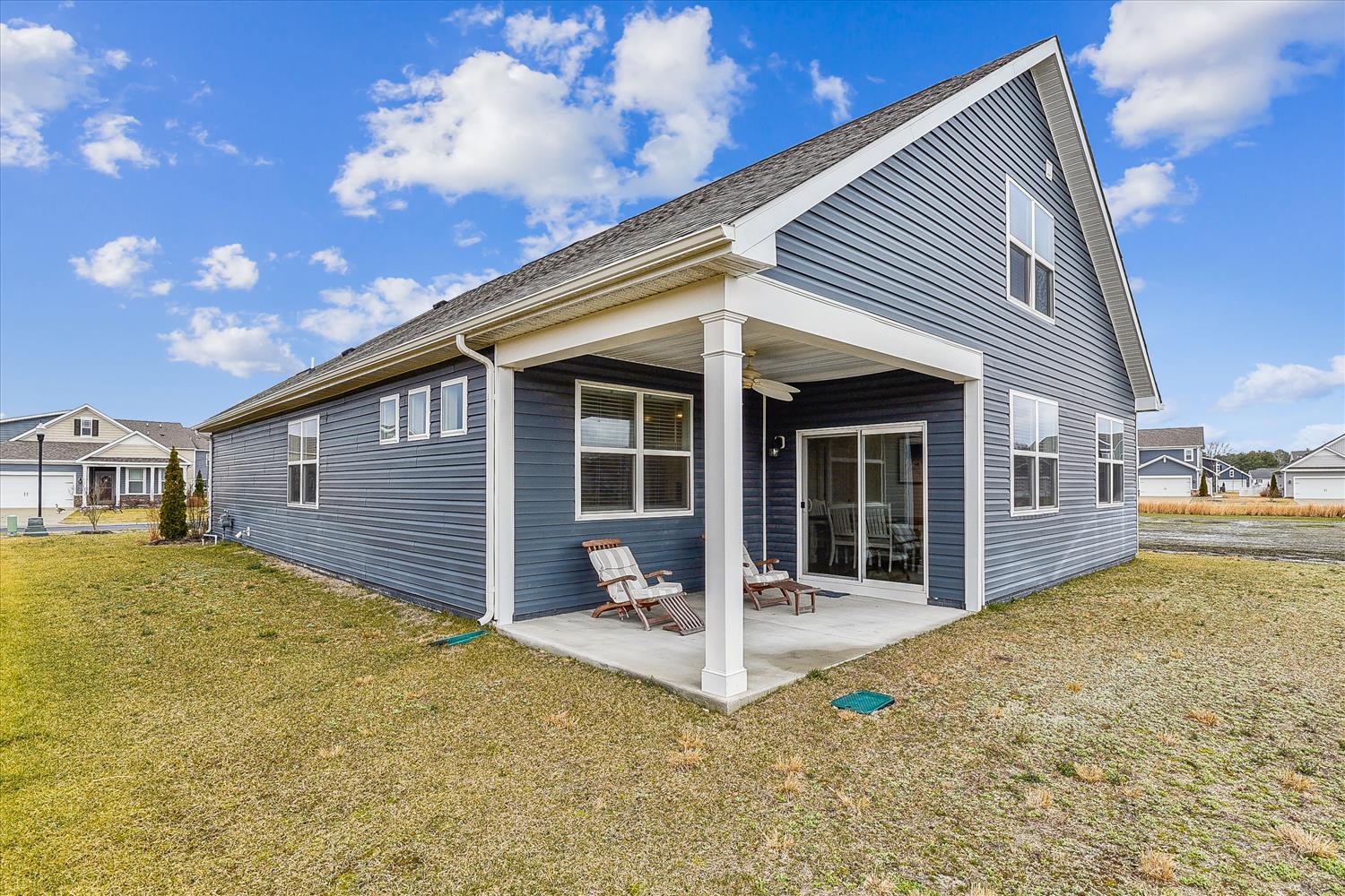 Modern single-story home with covered patio and outdoor seating, nestled in a quiet residential neighborhood.